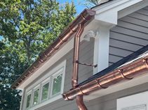 A close up of a copper gutter on the side of a house.