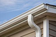 A close up of a white gutter on the side of a house.