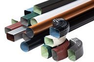 A bunch of different colored gutter pipes are stacked on top of each other on a white background.