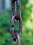 A close up of a rusty chain with a green background.