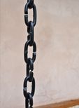 A close up of a black chain hanging from a pole.