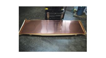 A large piece of copper is sitting on a concrete floor.