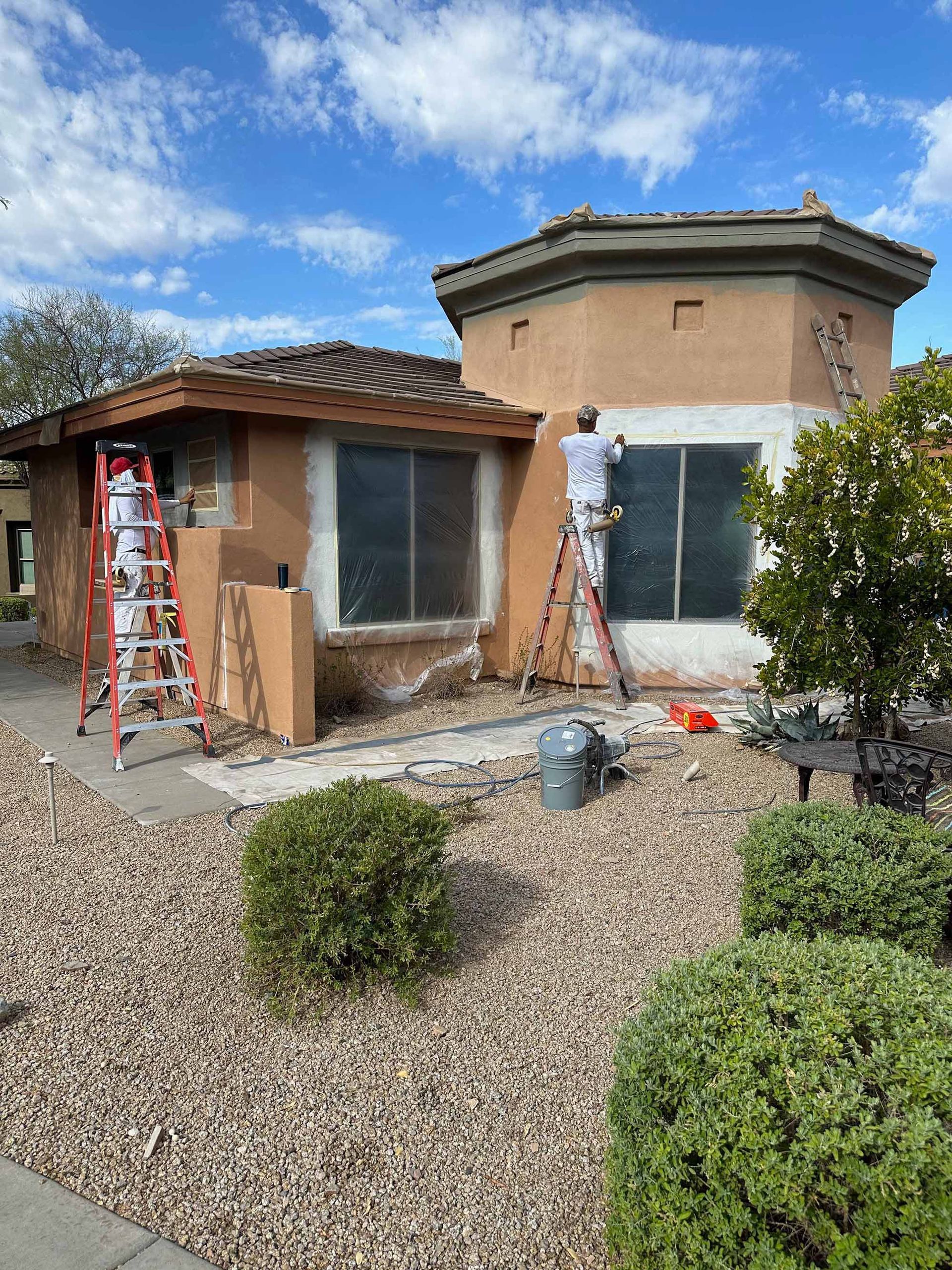 A man is standing on a ladder painting a house.