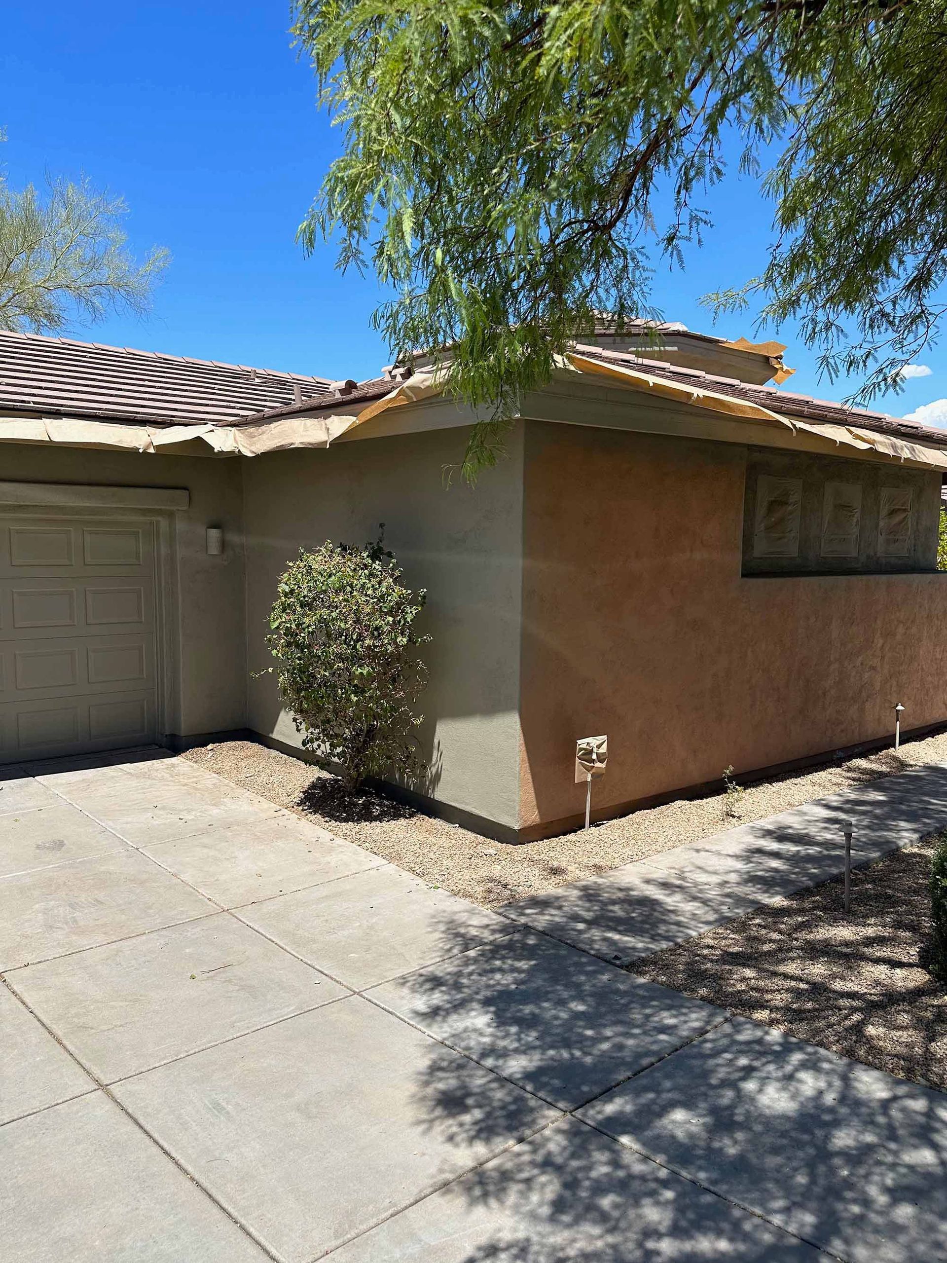A house with a garage and a tree in front of it.