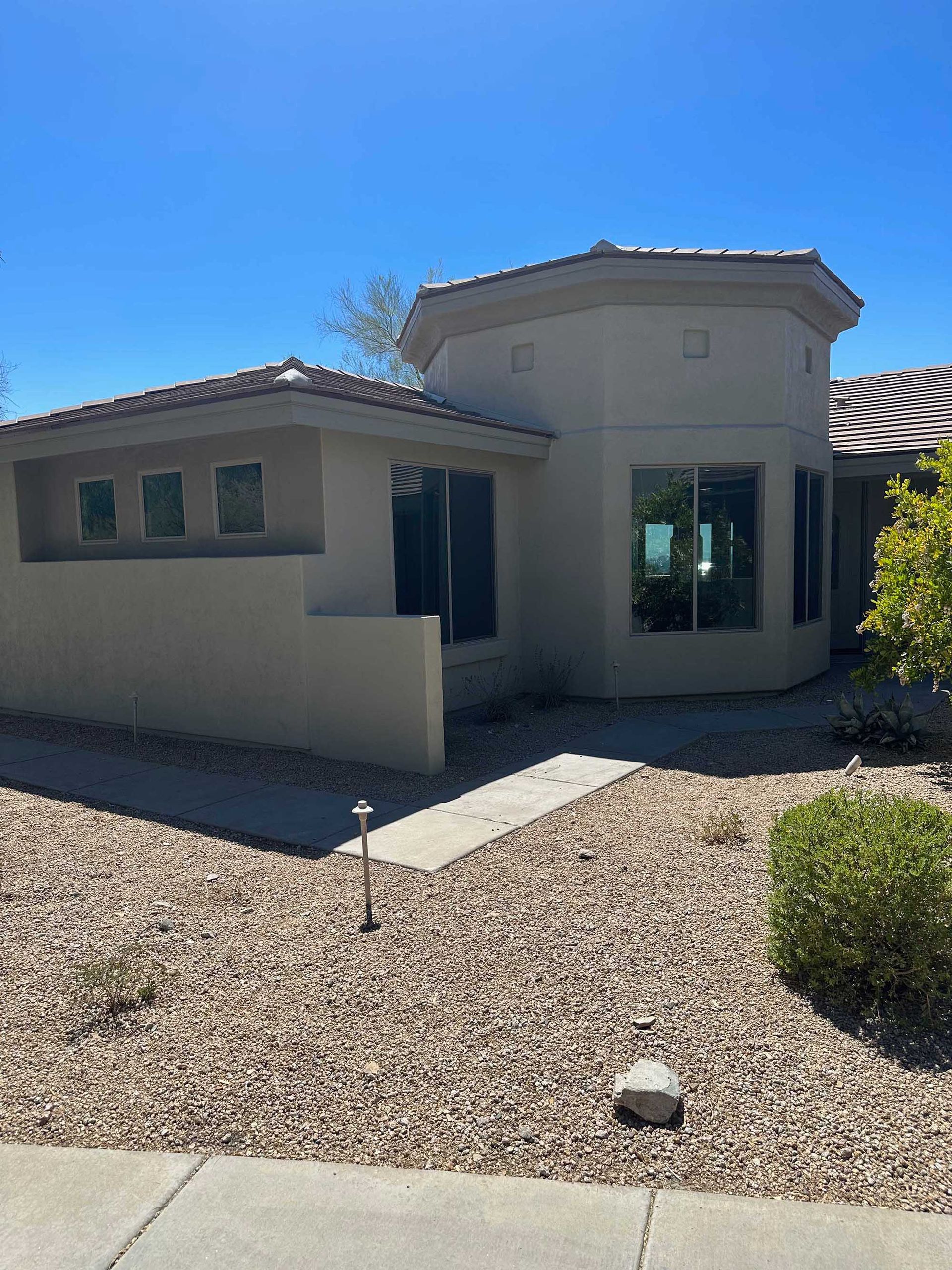 A house with a lot of windows and gravel in front of it
