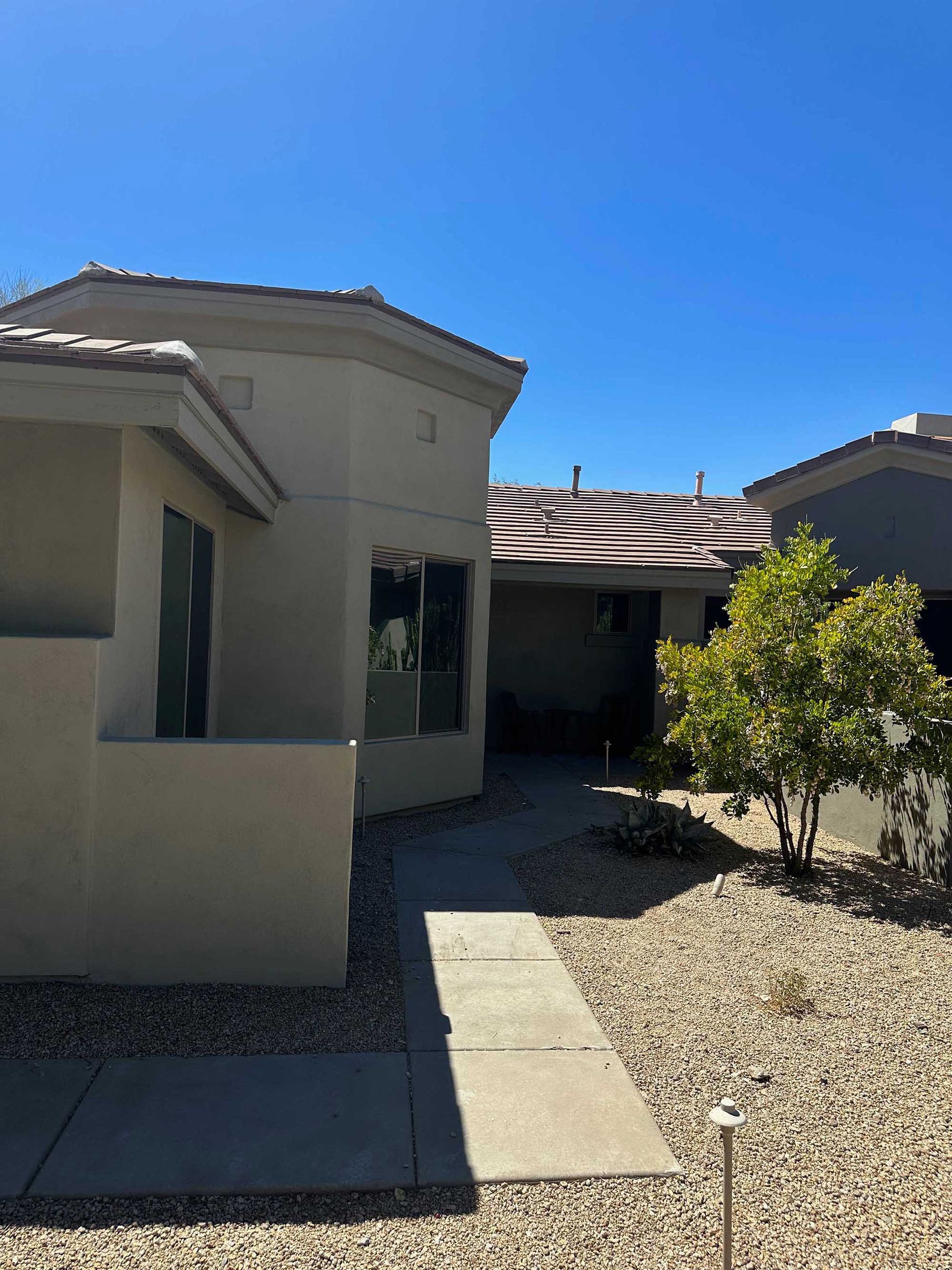 A house with a walkway leading to it and a blue sky in the background