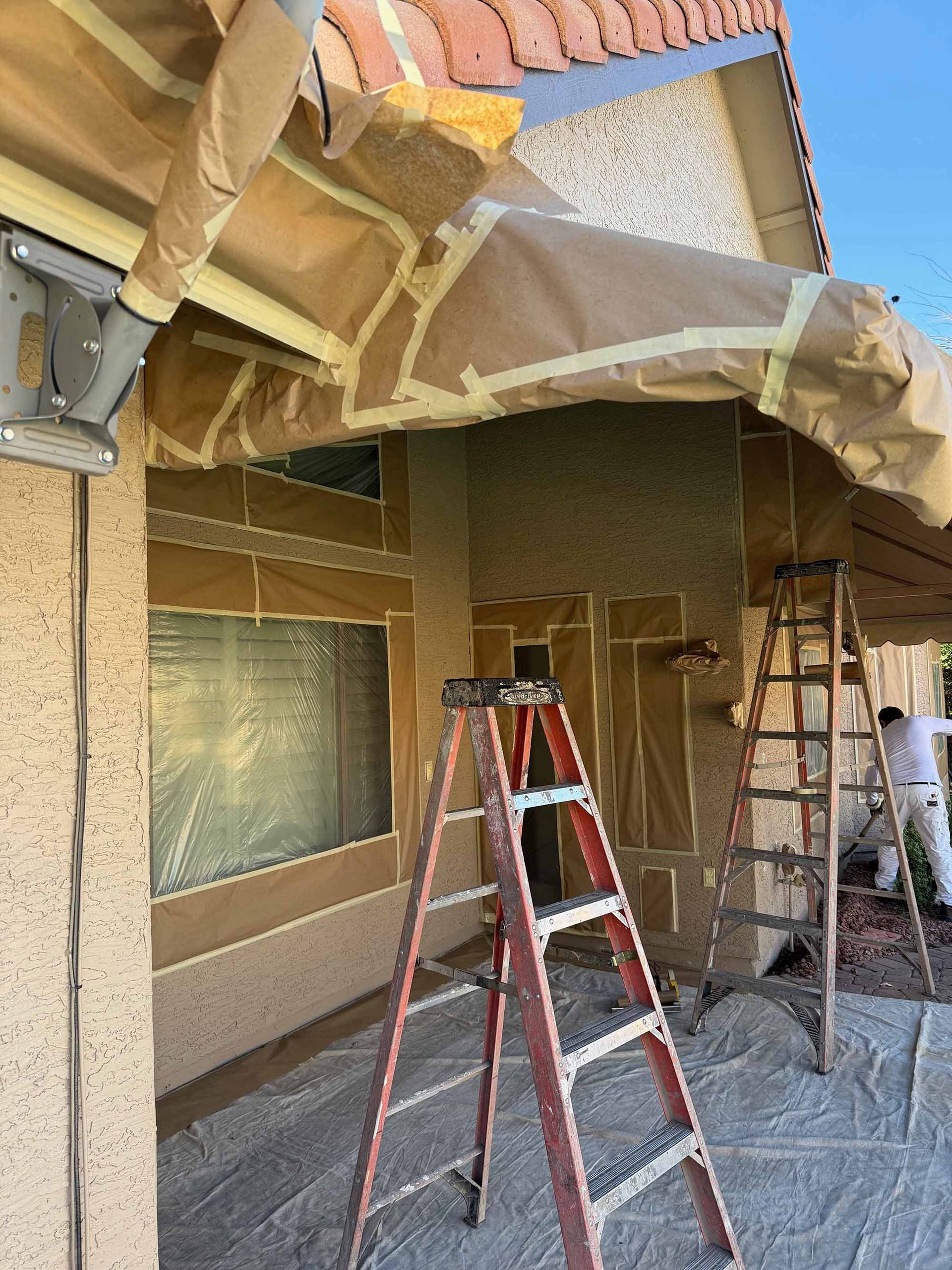 A ladder is sitting in front of a house that is being painted.