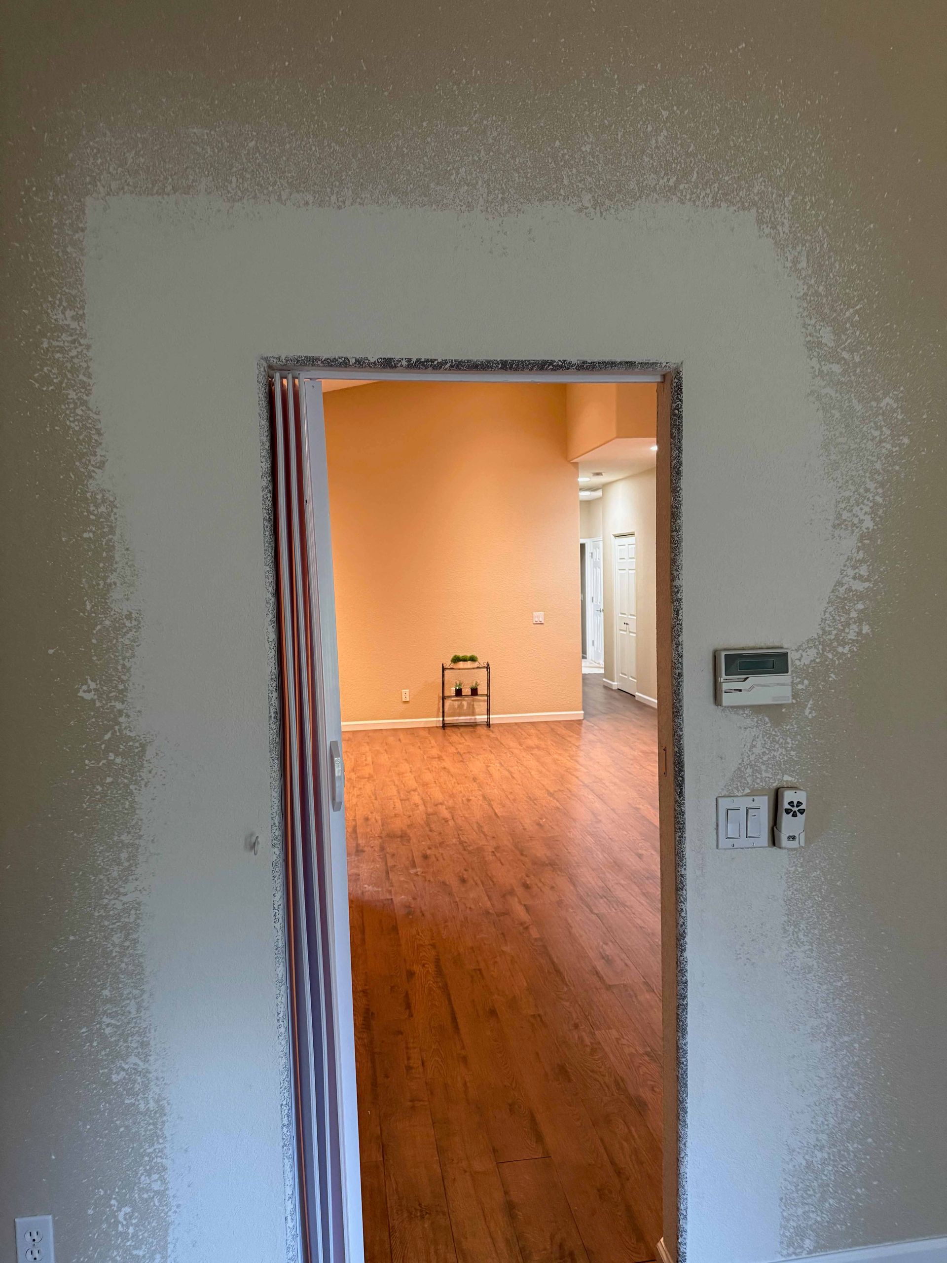 A doorway leading into a living room with hardwood floors.