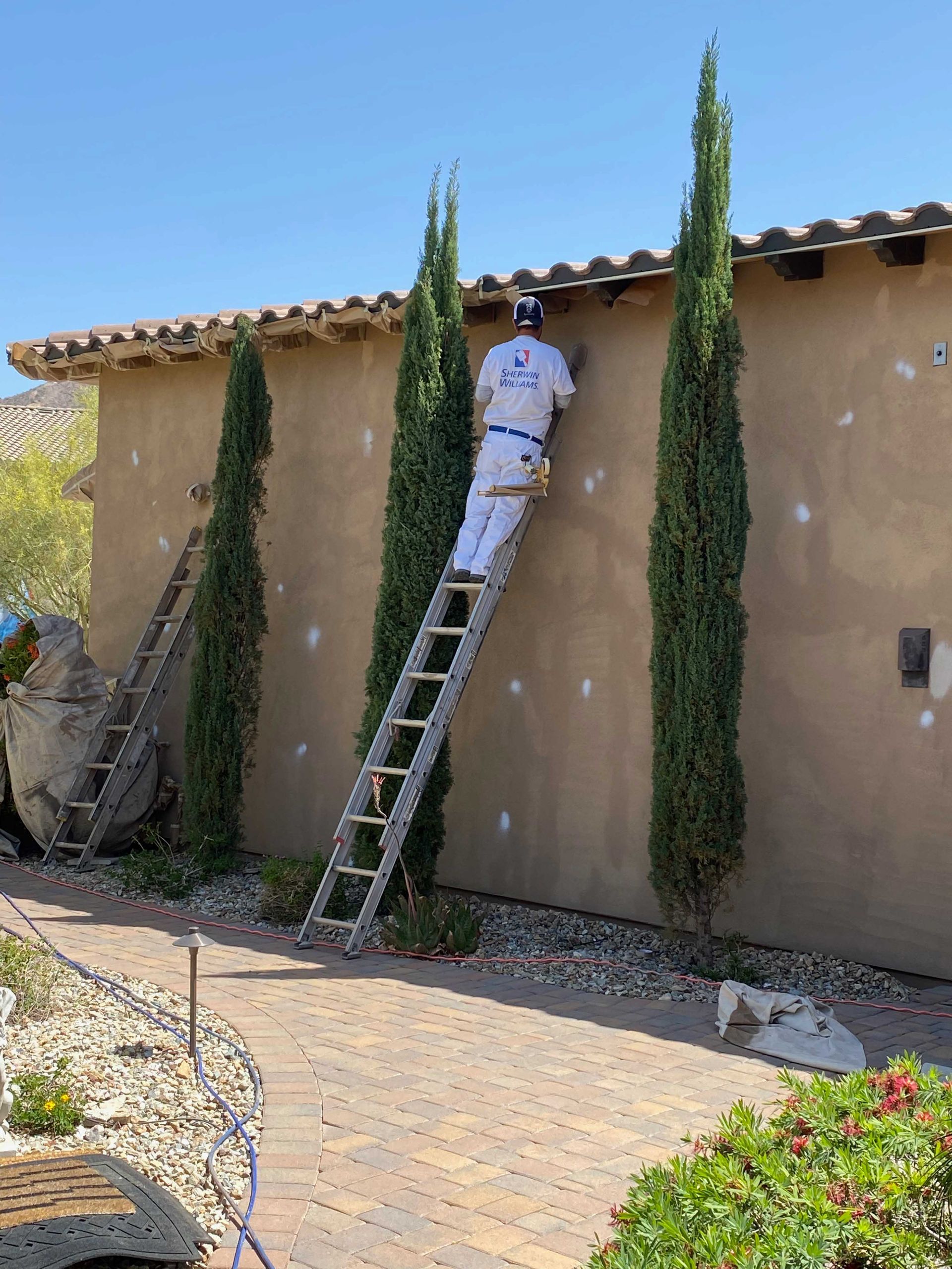 A man is standing on a ladder painting a wall.