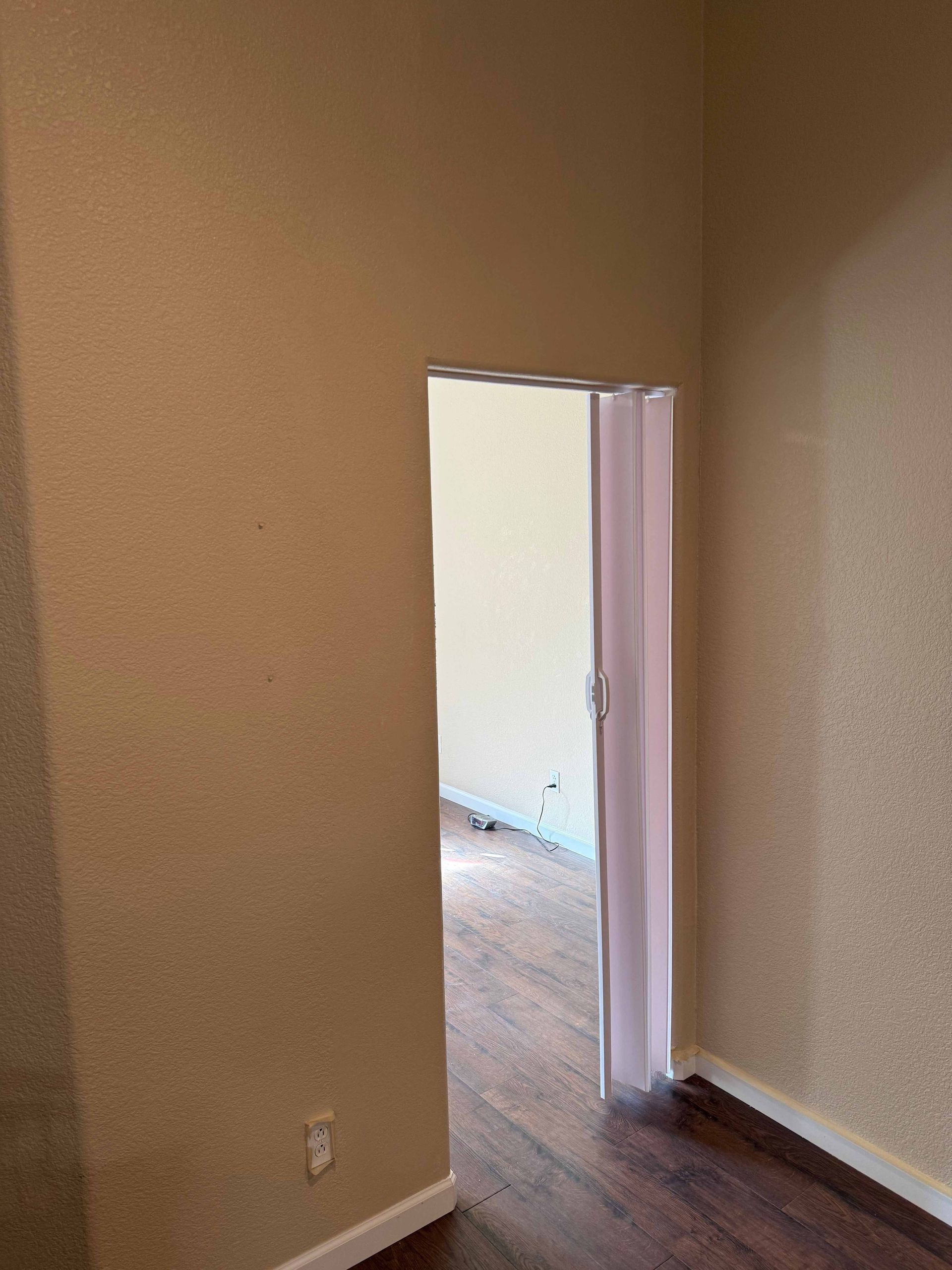 An empty room with a door open and a wooden floor.