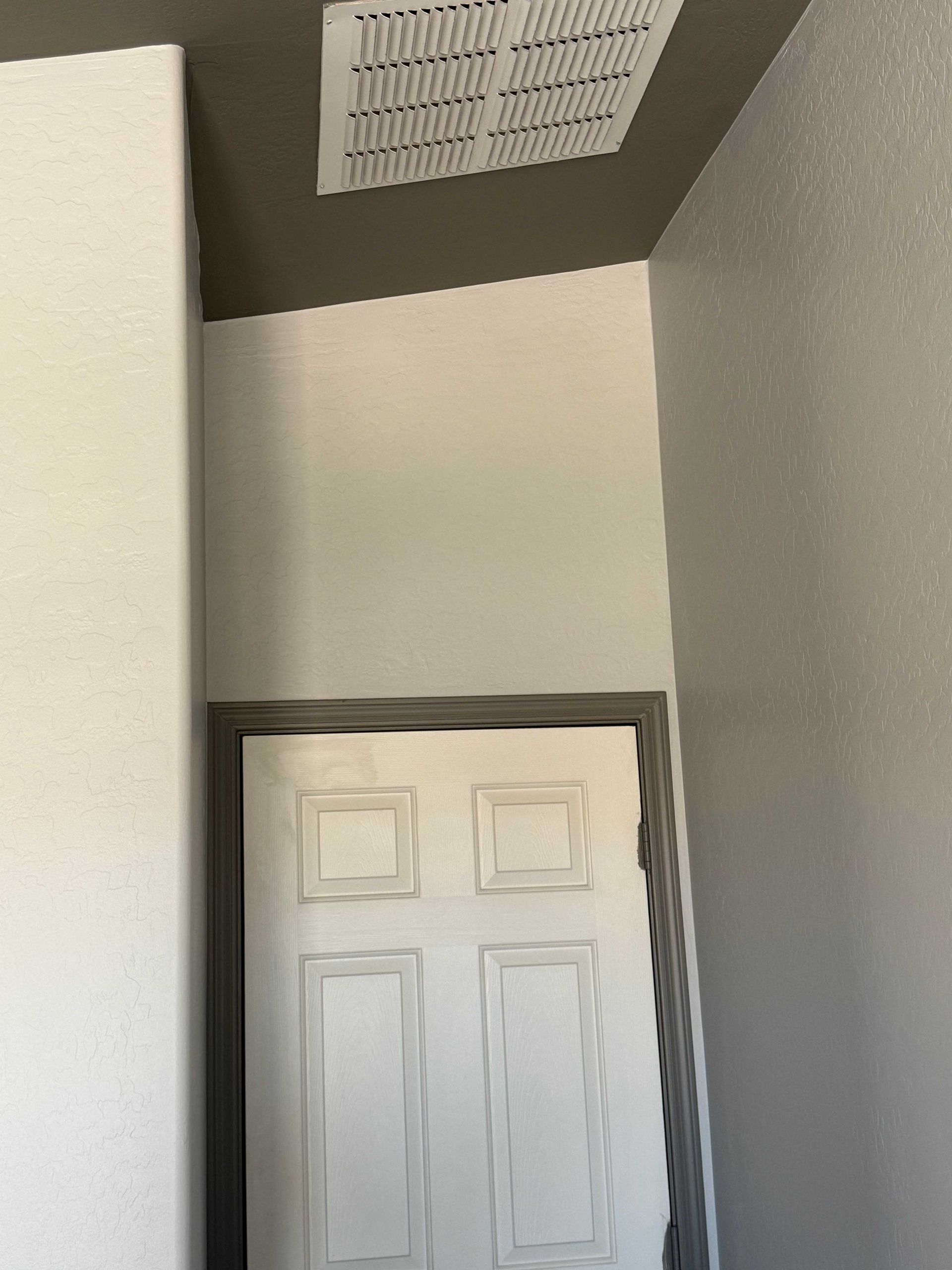A white door with a ceiling fan above it in a room.