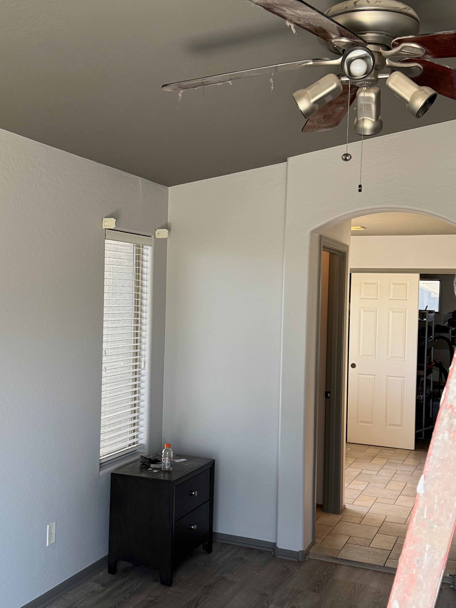 A bedroom with a ceiling fan and a window.