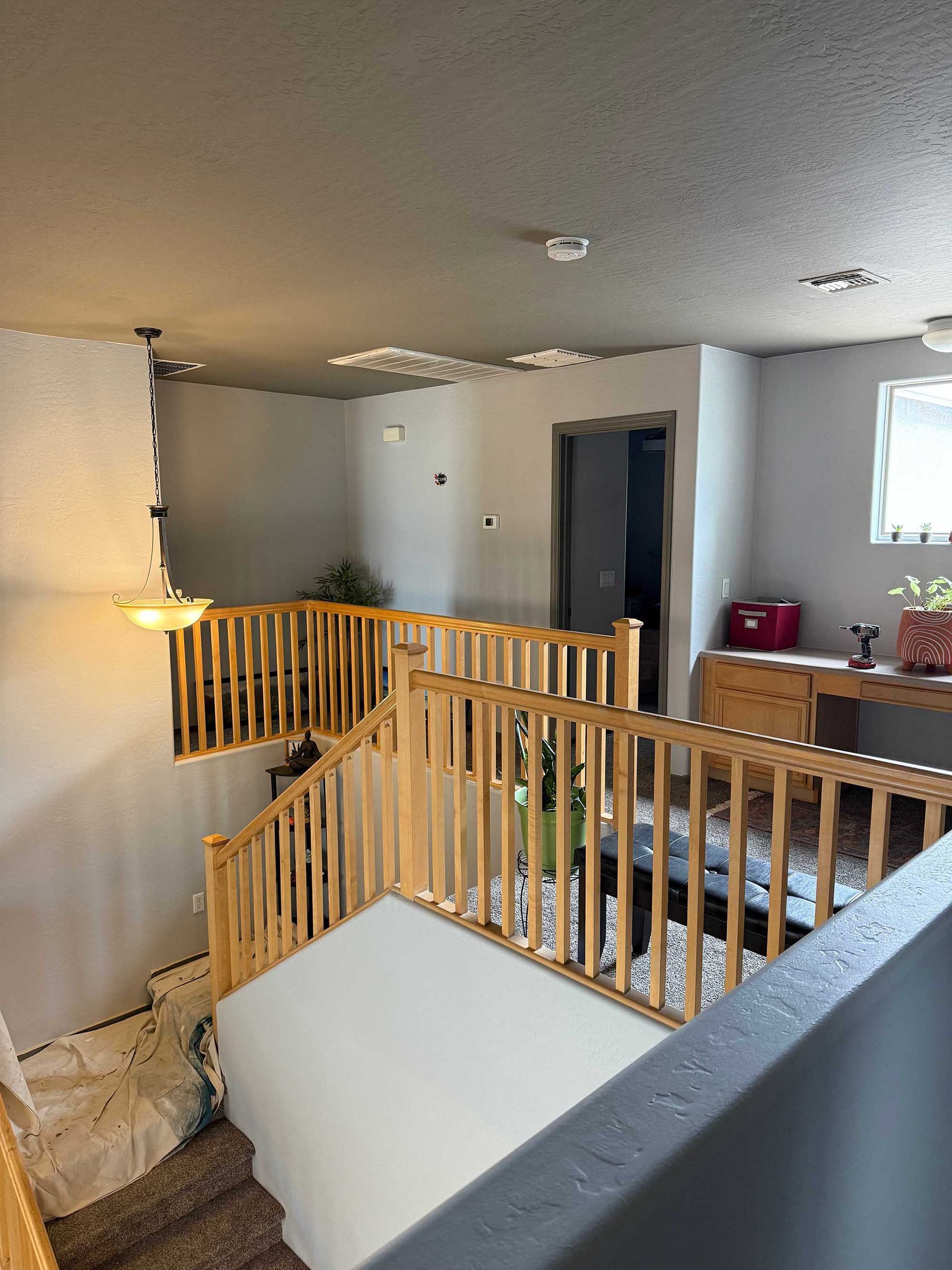A staircase in a house with a wooden railing and a broken ceiling.