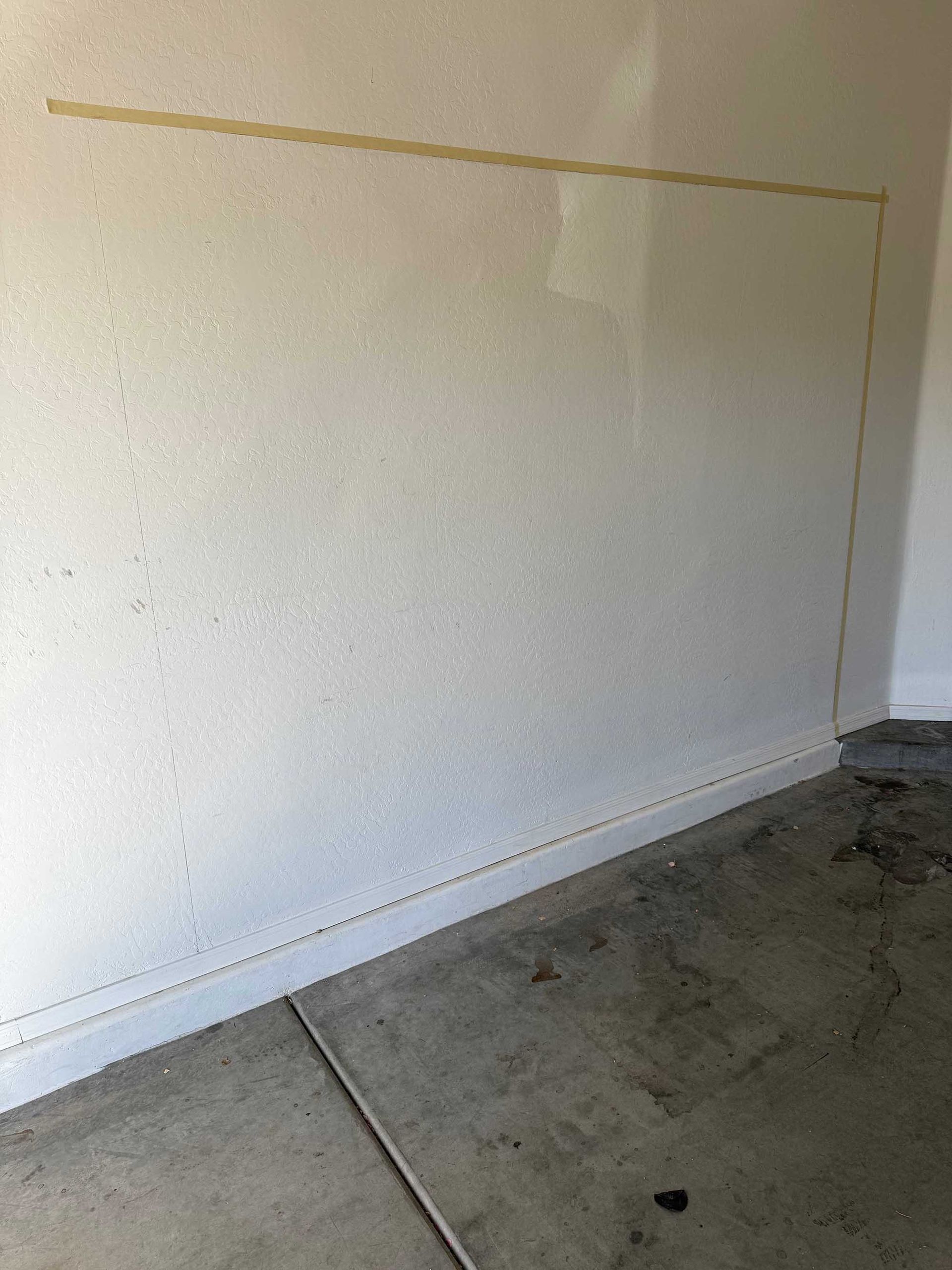A garage with a white wall and a concrete floor.