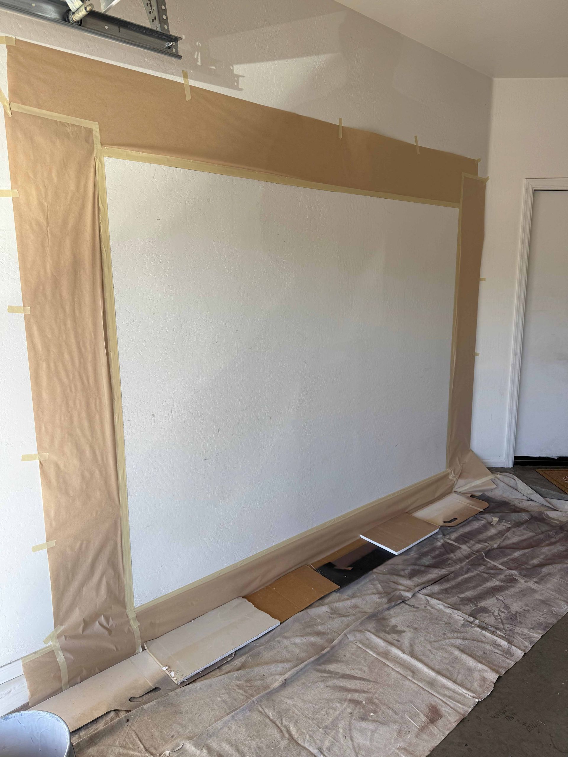 A large white wall is being painted in a garage.