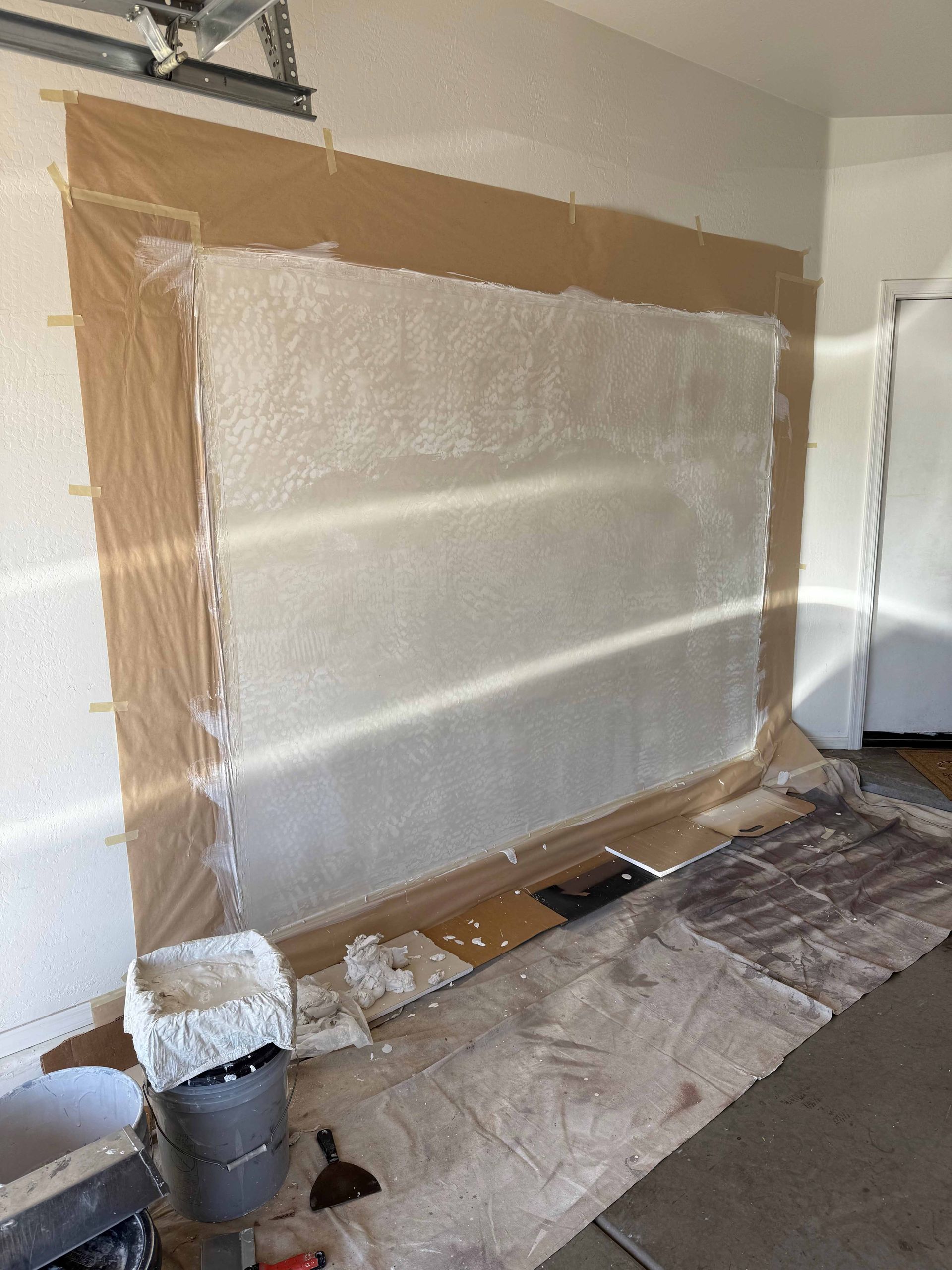 A large wall is being painted in a garage.
