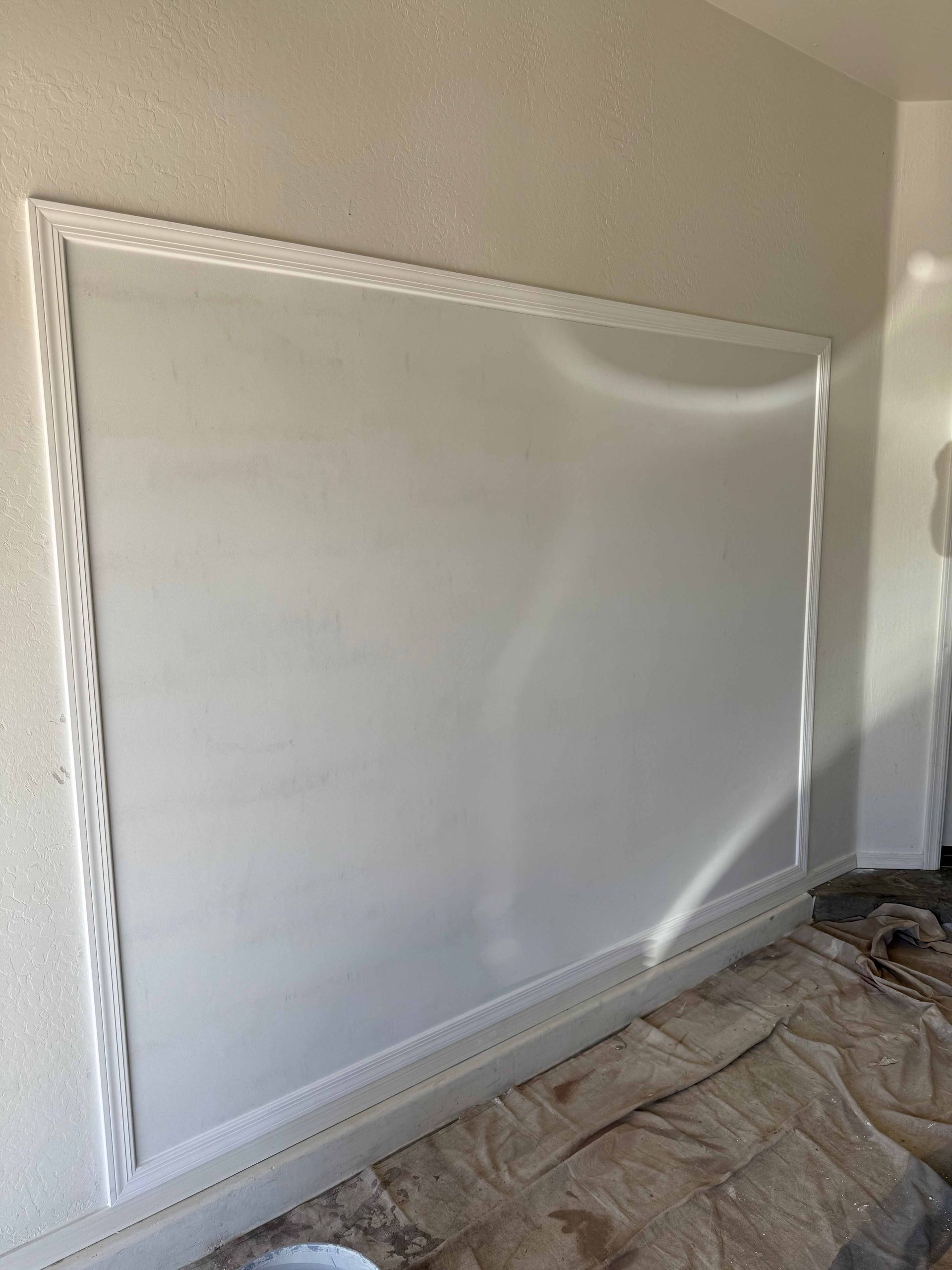 A large white board is sitting on the floor in a room.