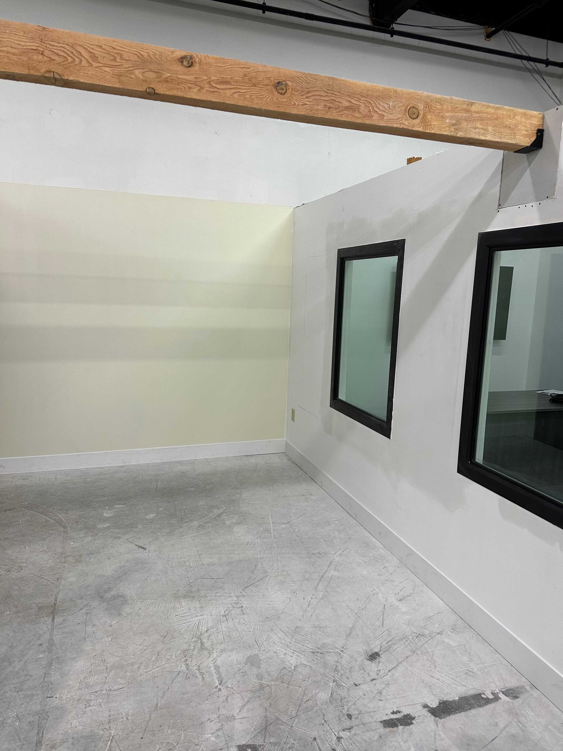 An empty room with two windows and a wooden beam.