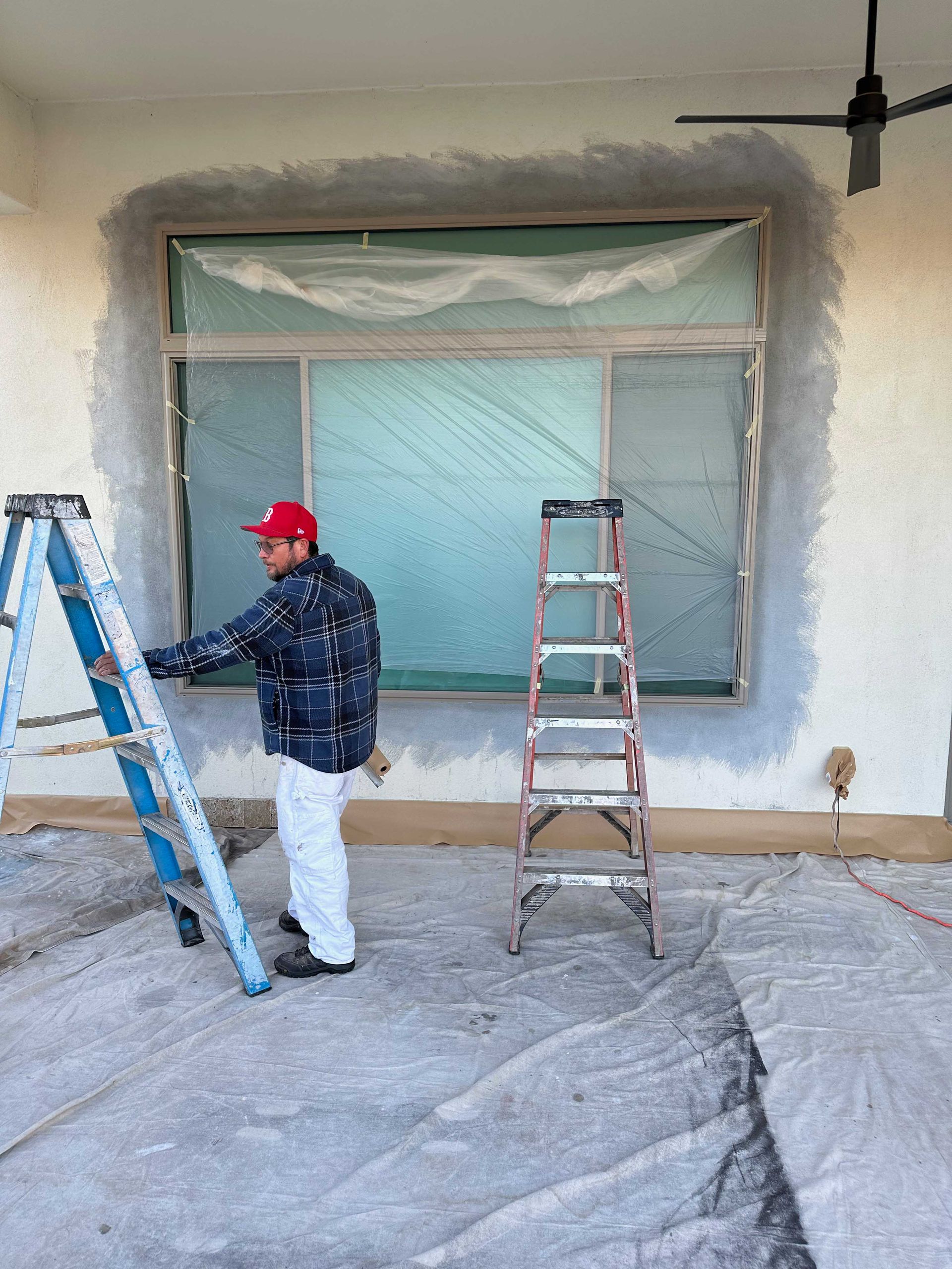 A man is painting a window with a ladder