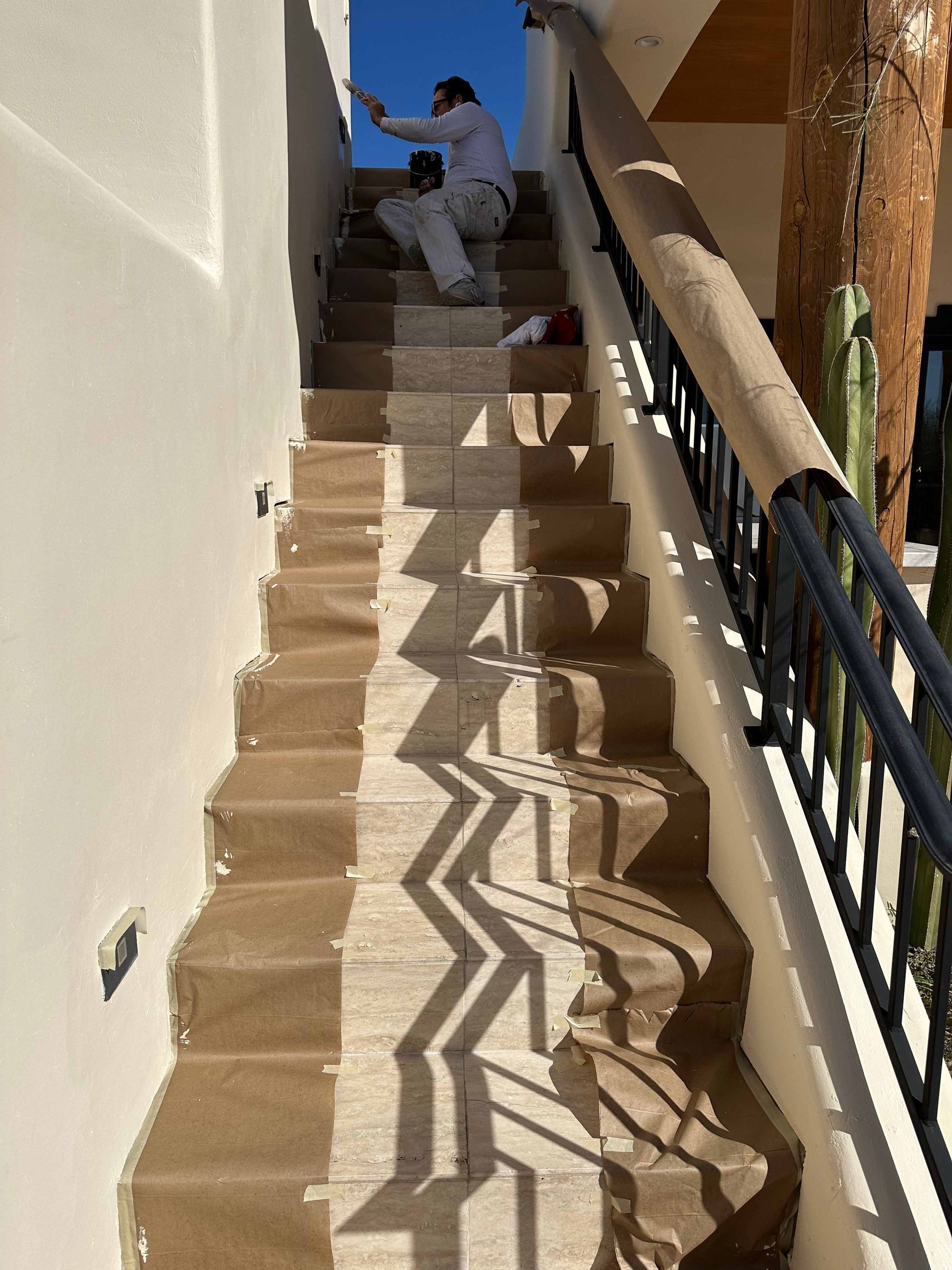 A man is painting a wall on a set of stairs.