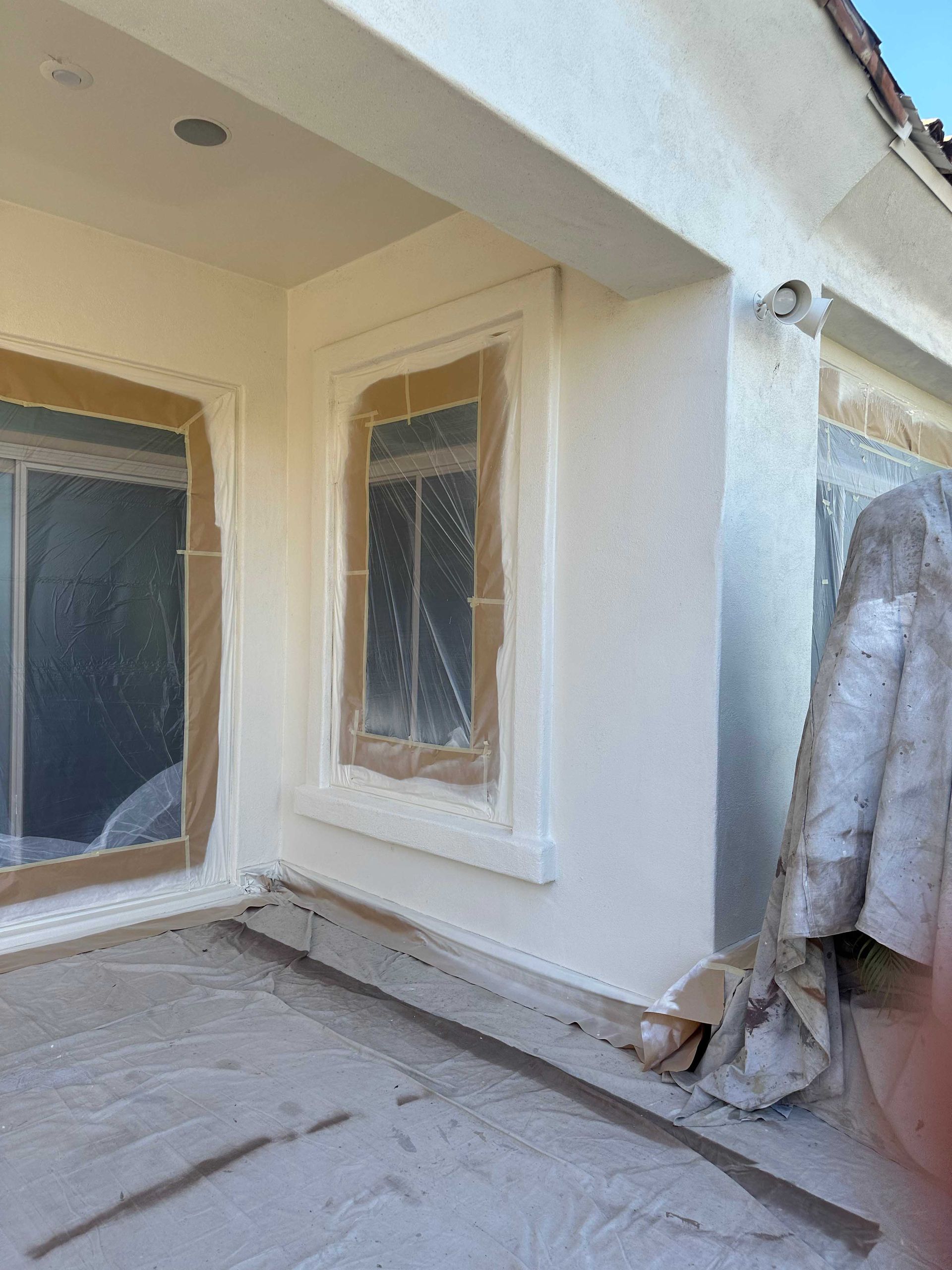 The outside of a house is being painted white.