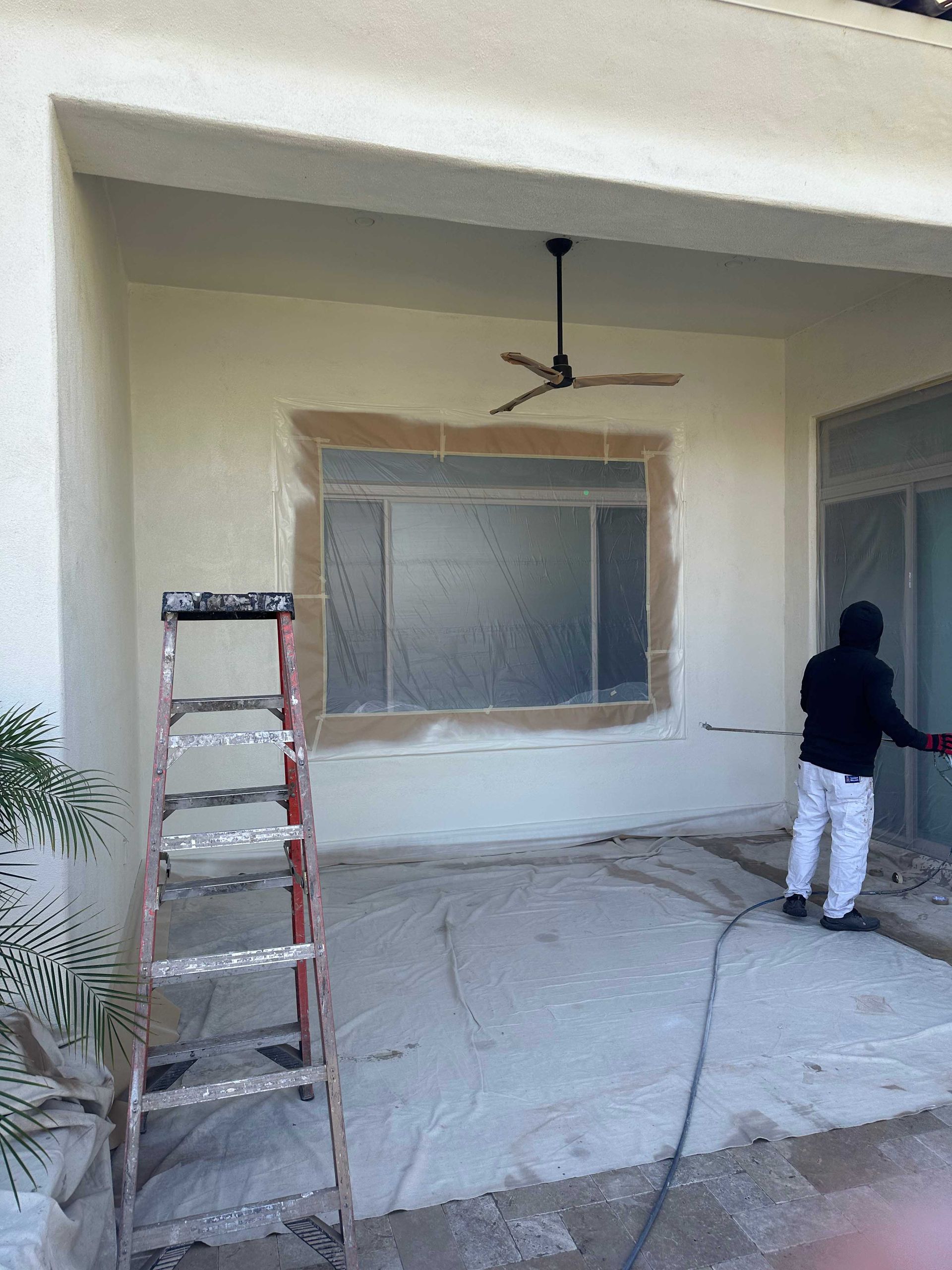 A man is painting a wall with a ladder in the background