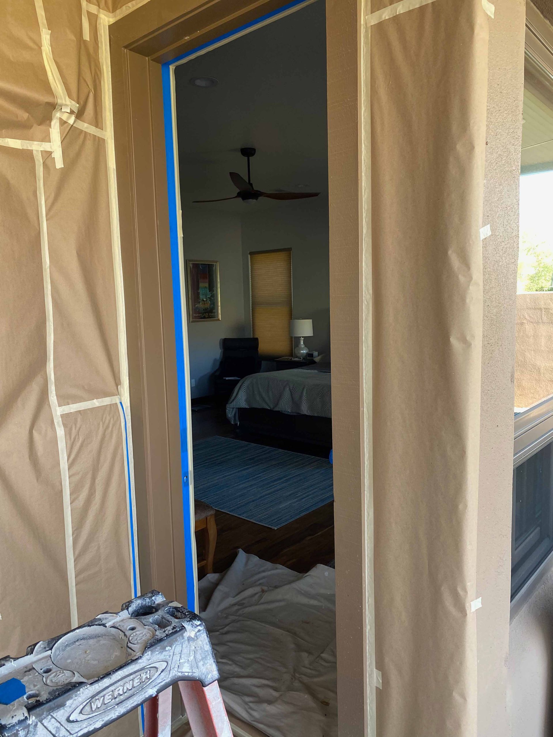 A ladder is sitting in front of a door that is being painted.