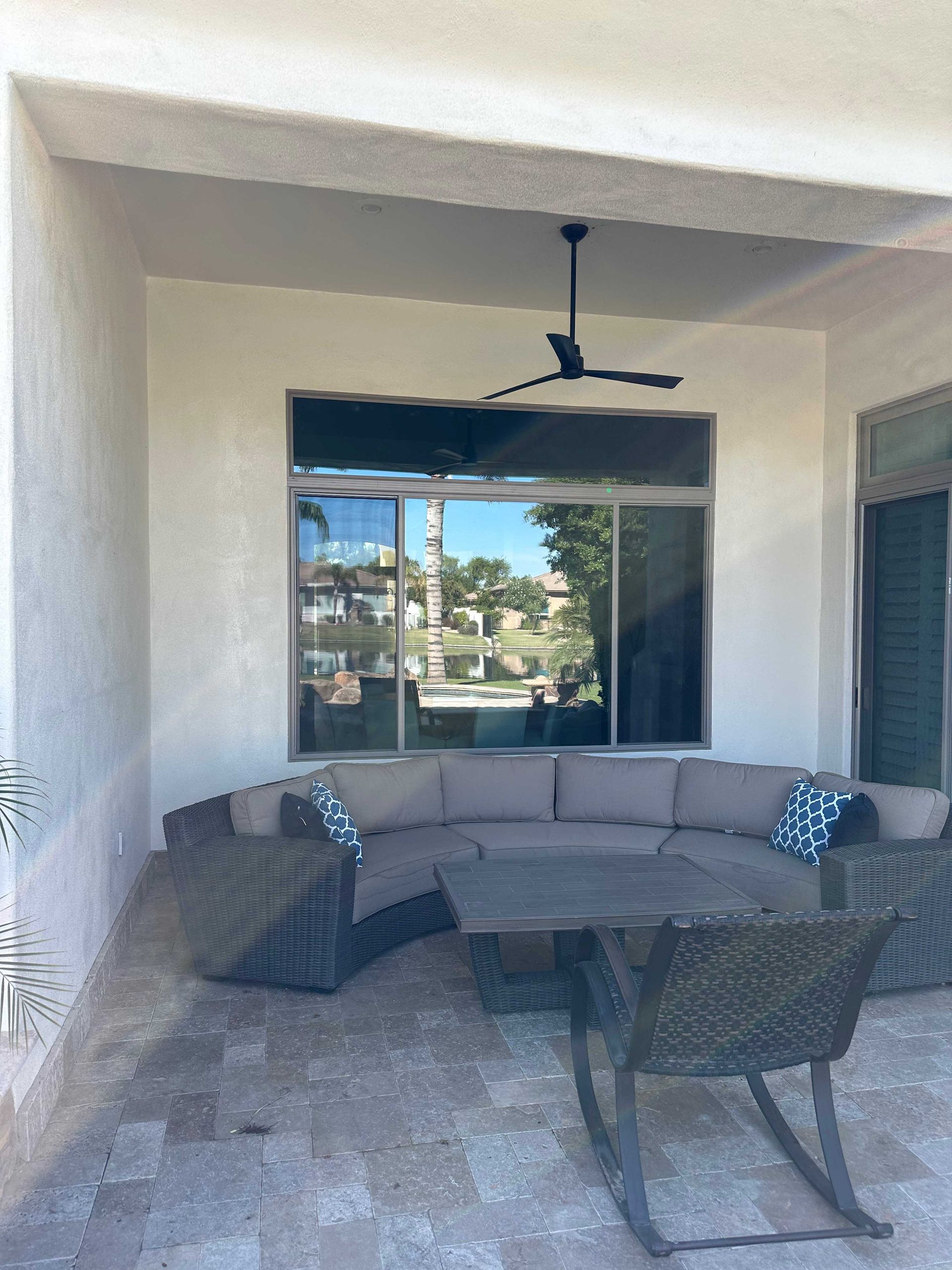 A patio with a couch , chairs , a table and a ceiling fan.