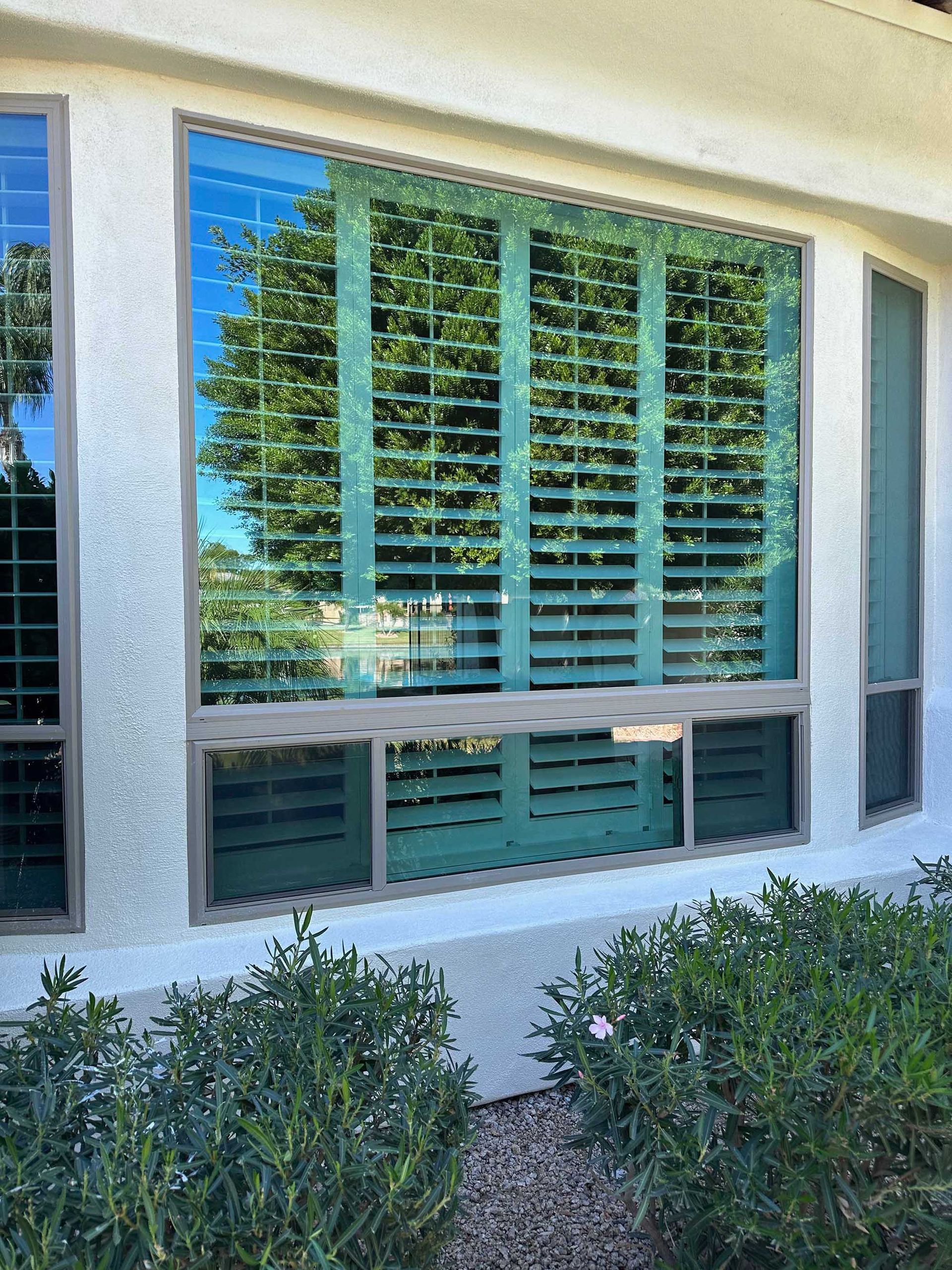 A large window with shutters on it is on the side of a building.