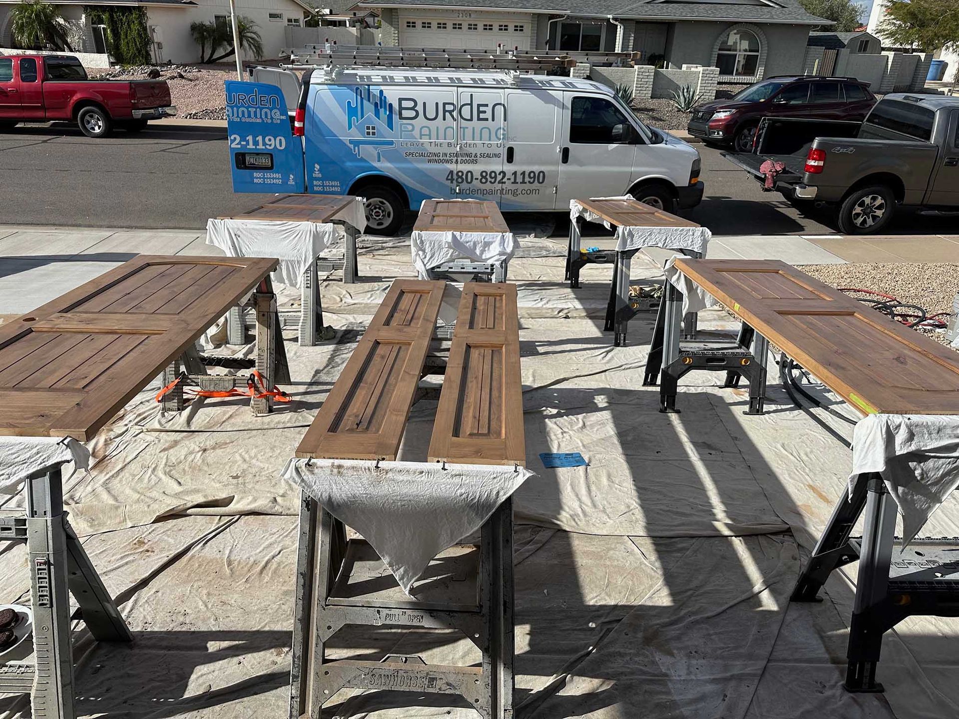 A white van with the word burden on it is parked next to a bunch of wooden tables.