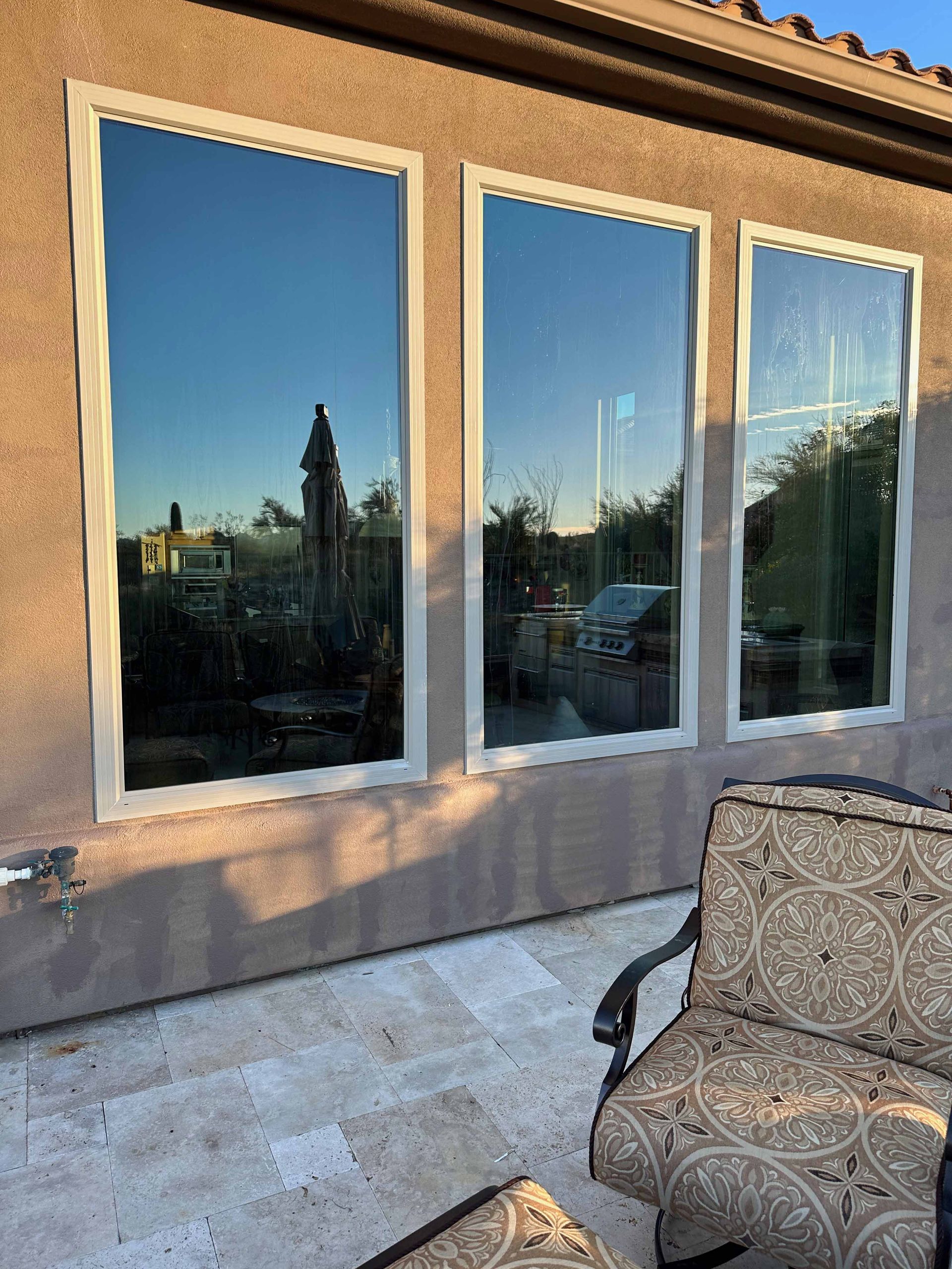 A house with three windows and a couch in front of it.
