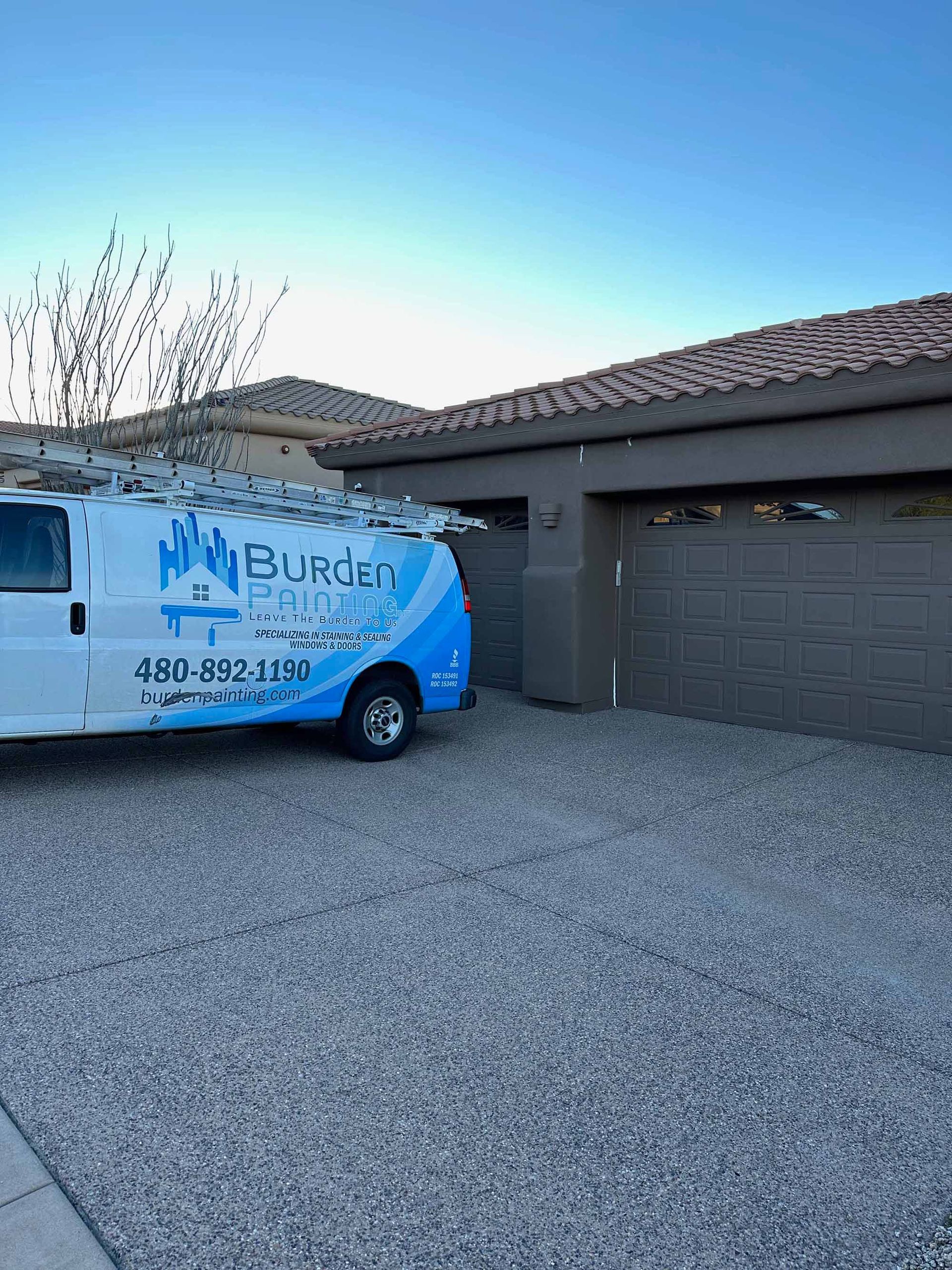 A blue and white van is parked in front of a house.