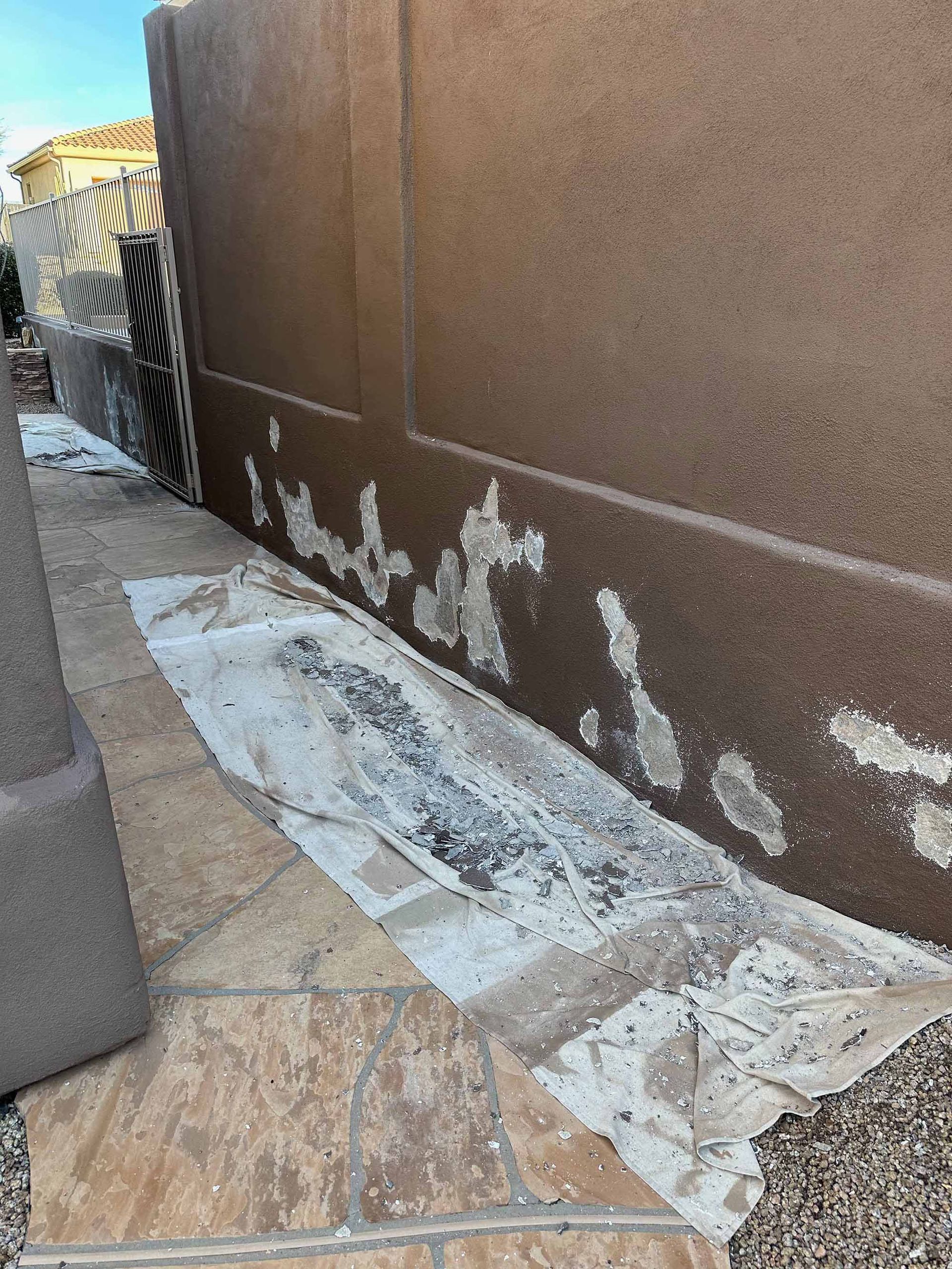 A wall with a lot of peeling paint on it is being painted.