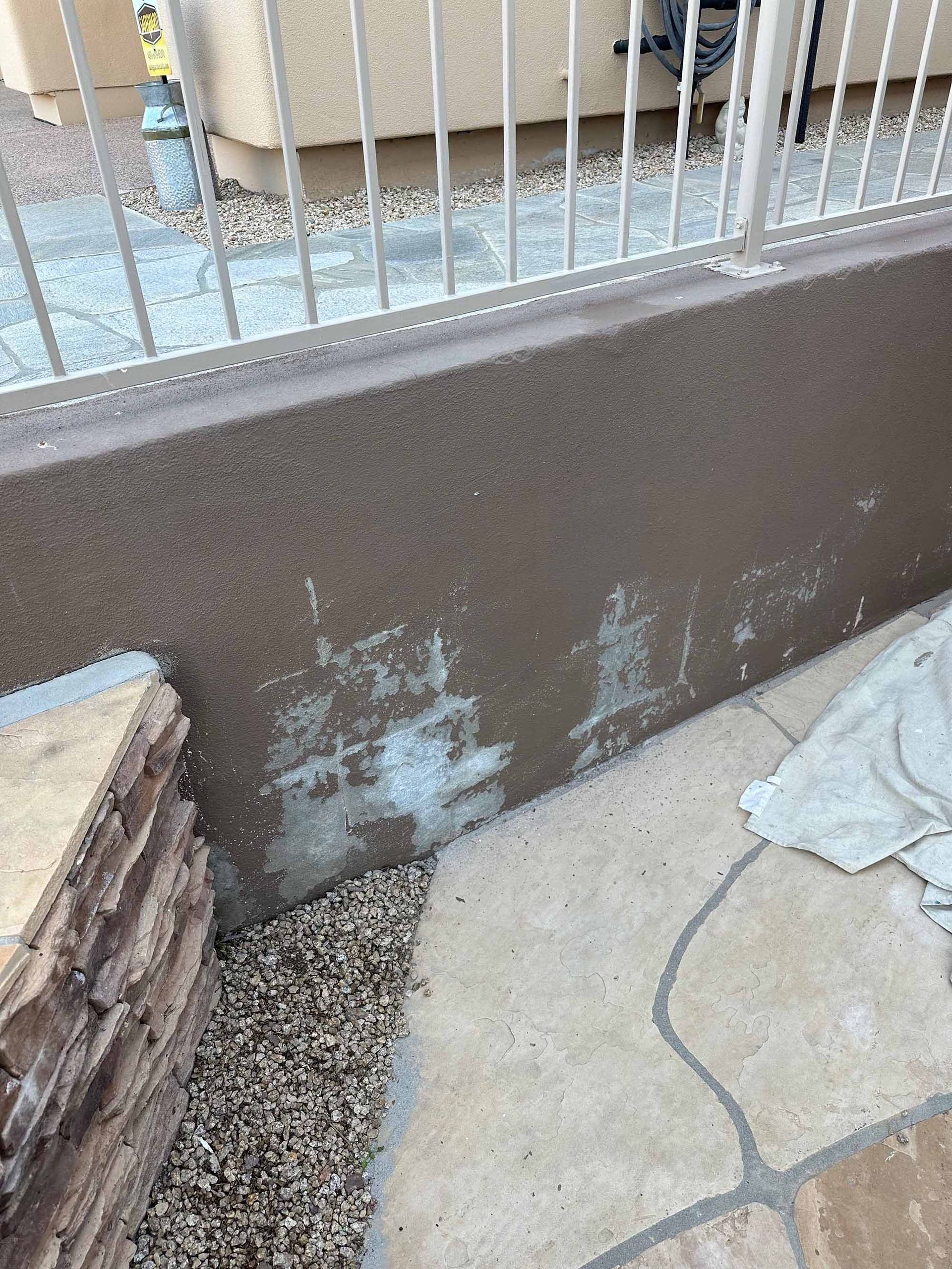 A close up of a wall with a fence in the background.