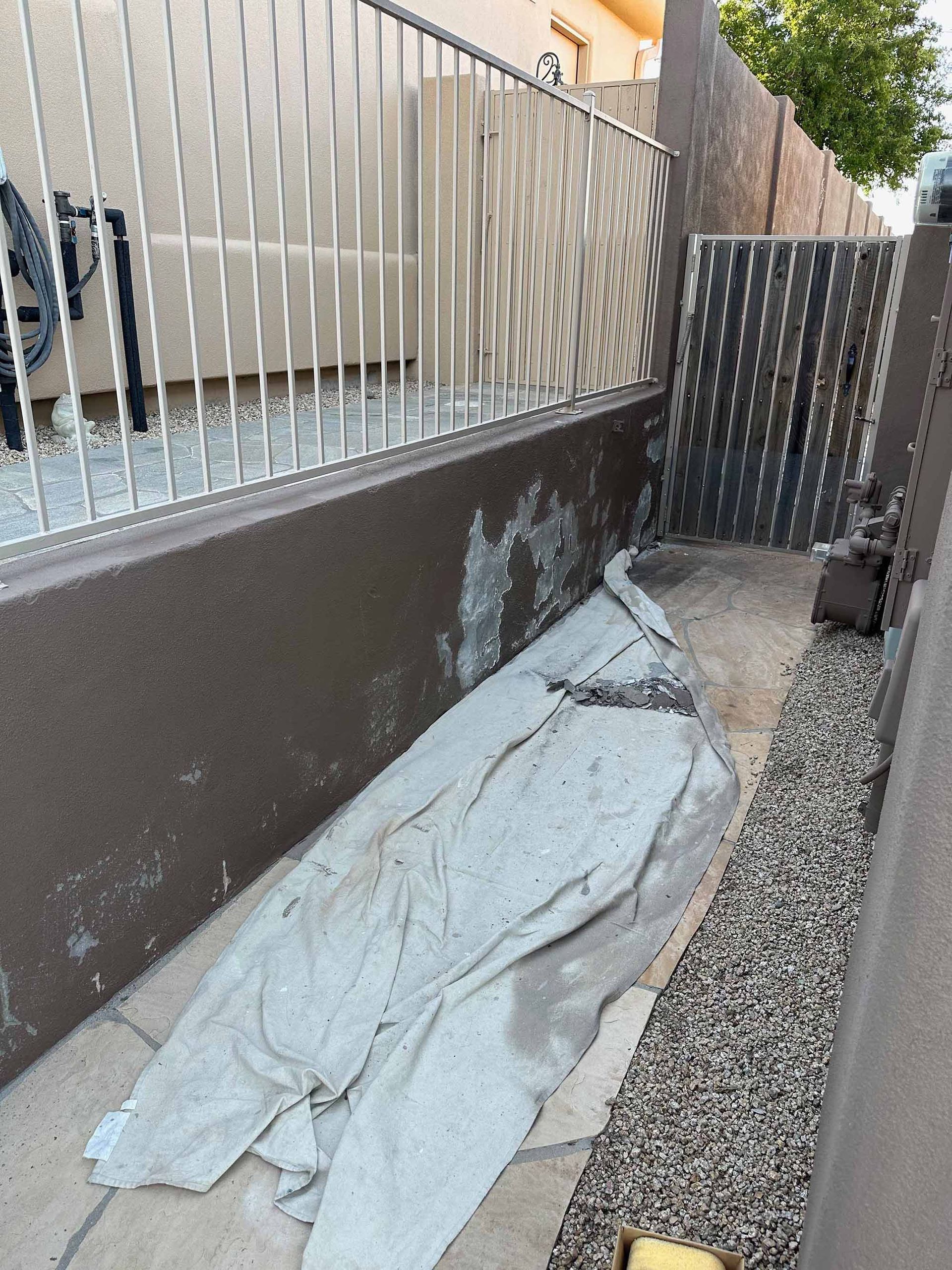 A blanket is laying on the ground next to a fence.