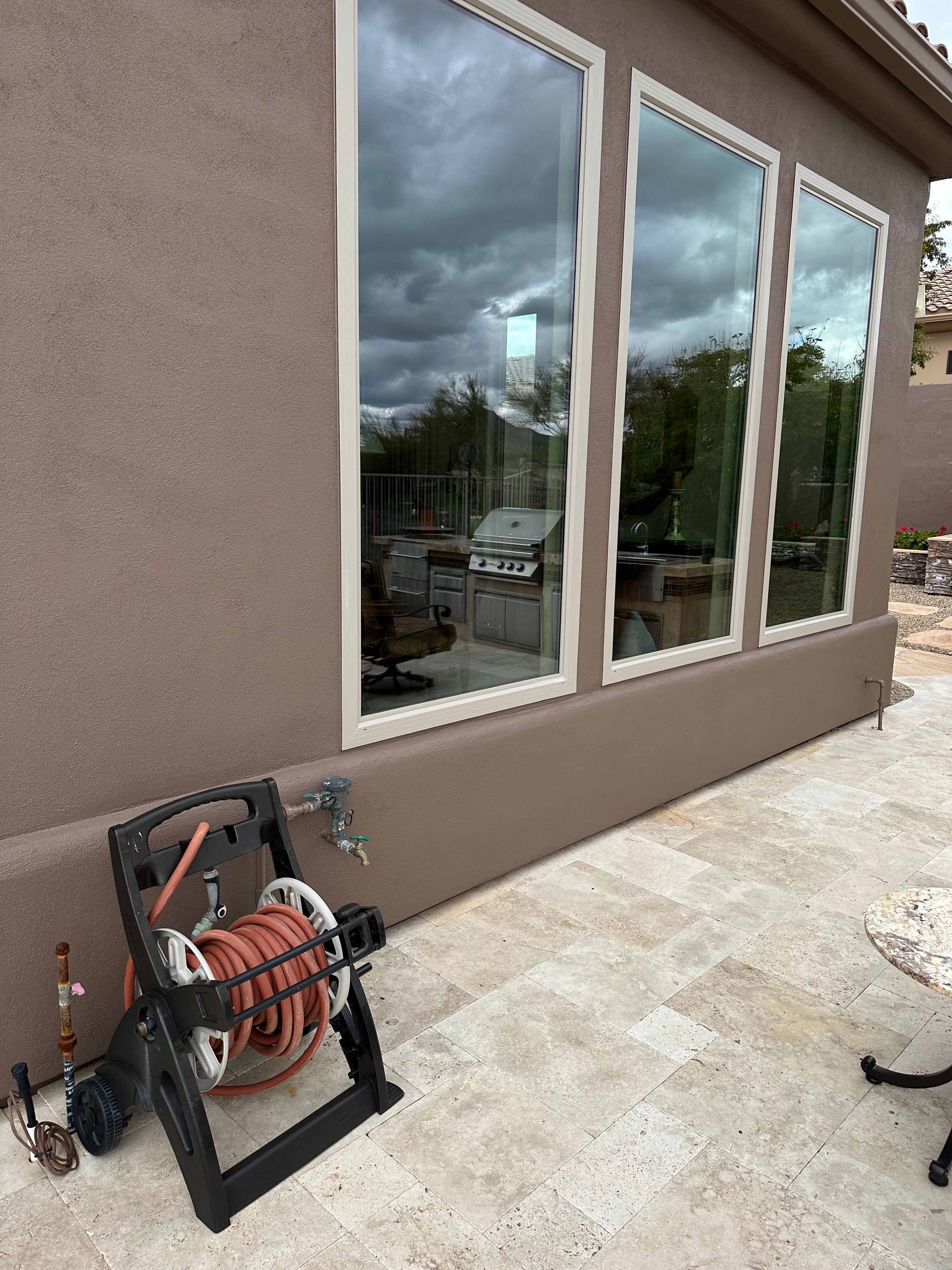 A hose reel is sitting on the side of a building next to a window.