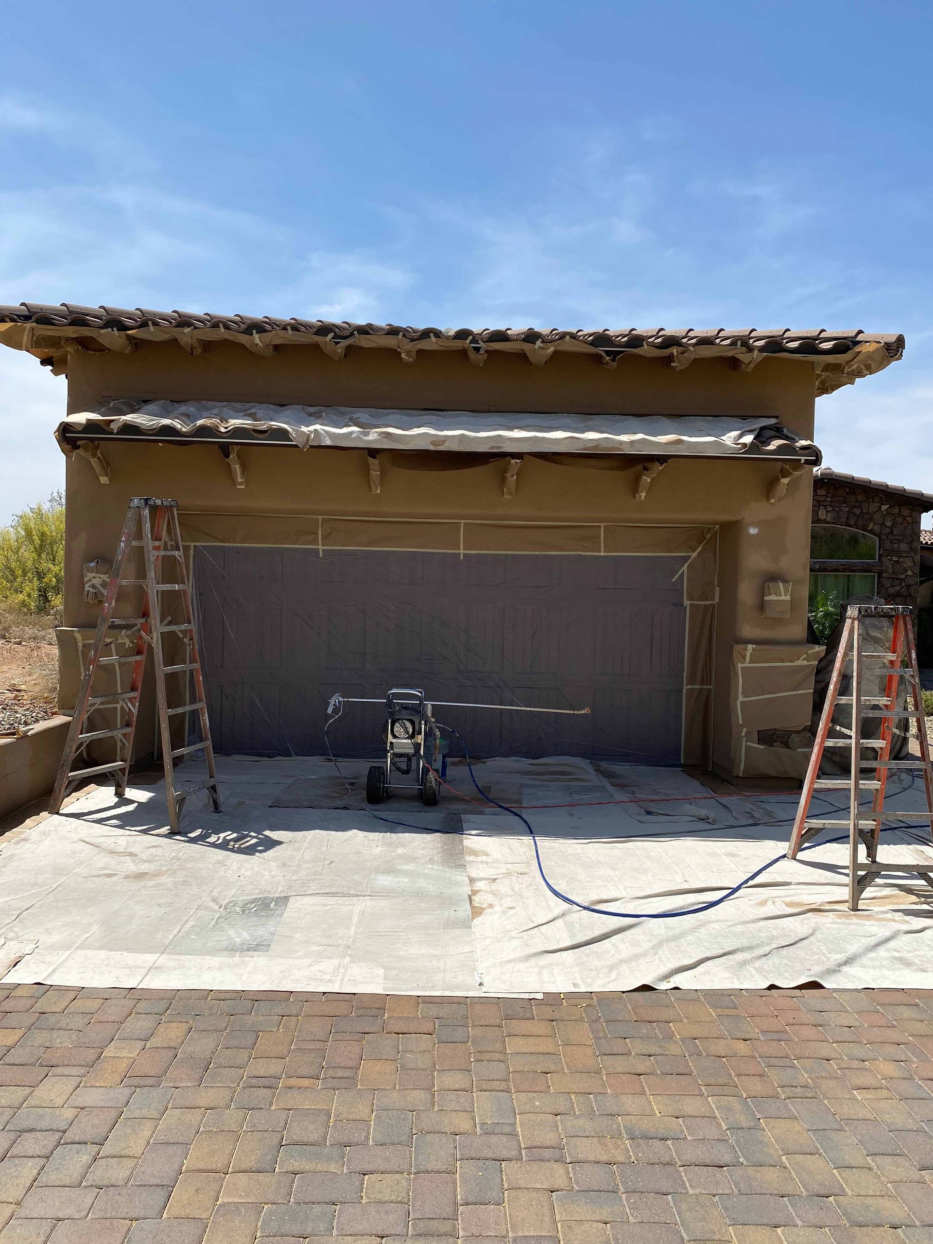 A garage door is being painted in front of a house.