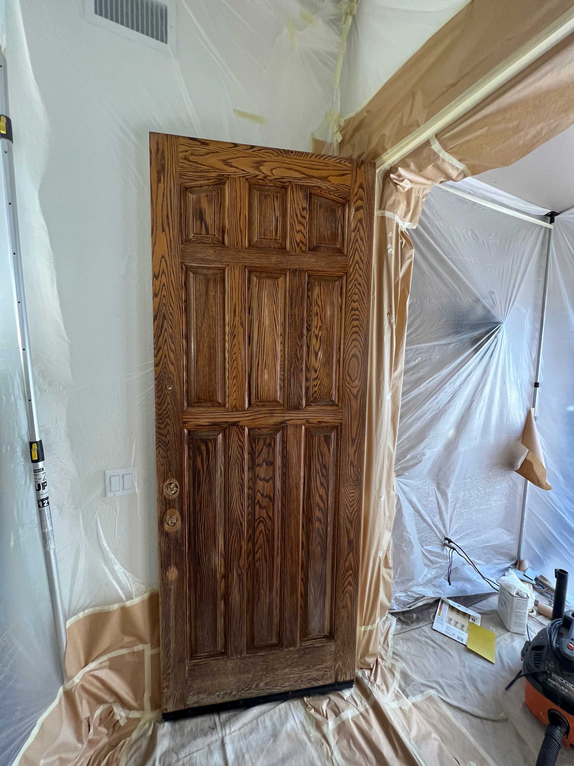 A wooden door is being painted in a room.