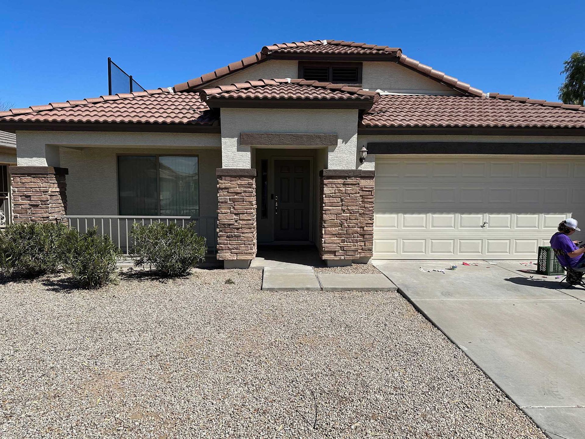 A man sits in a chair in front of a house