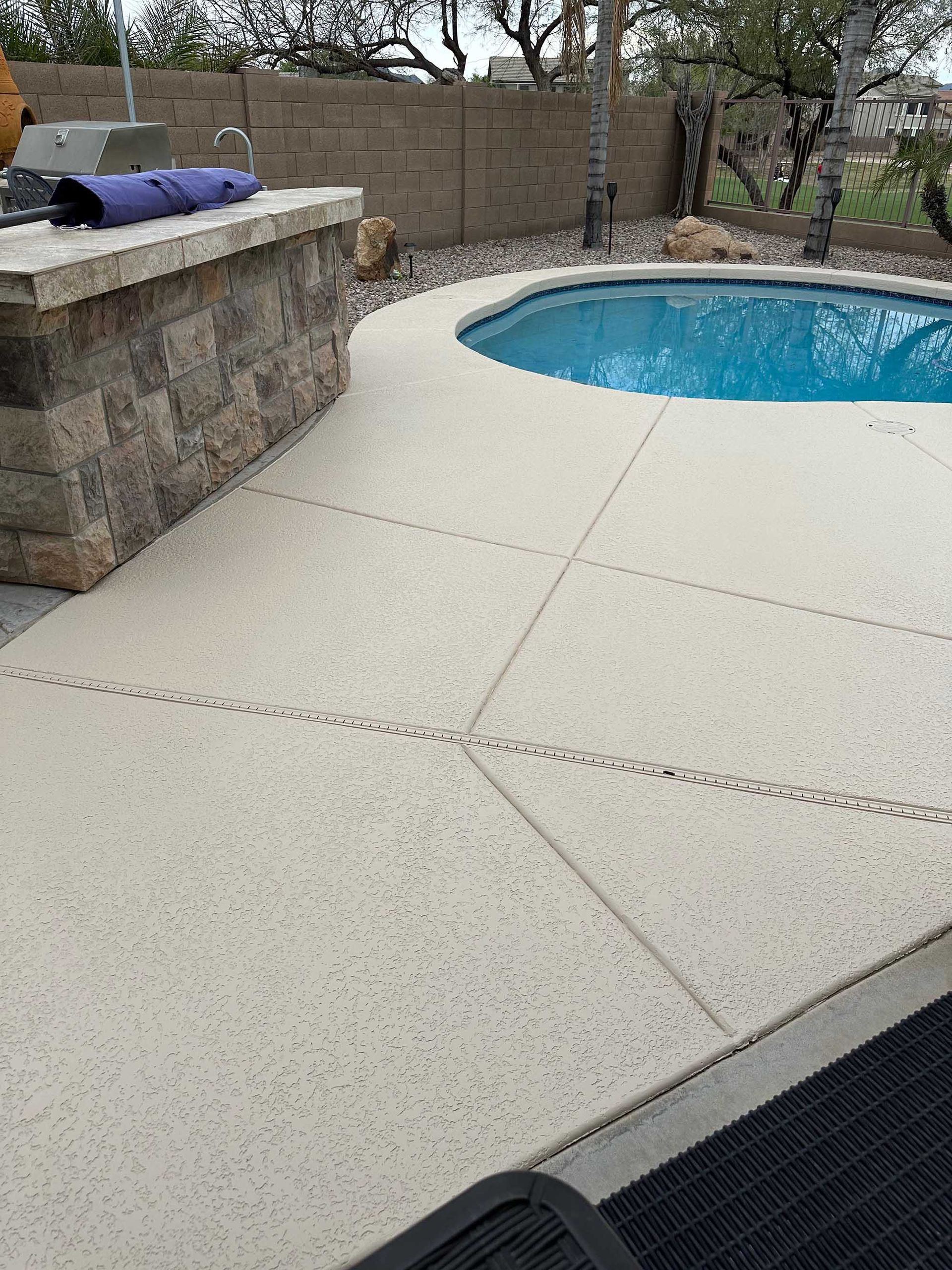 A patio with a swimming pool and a grill.