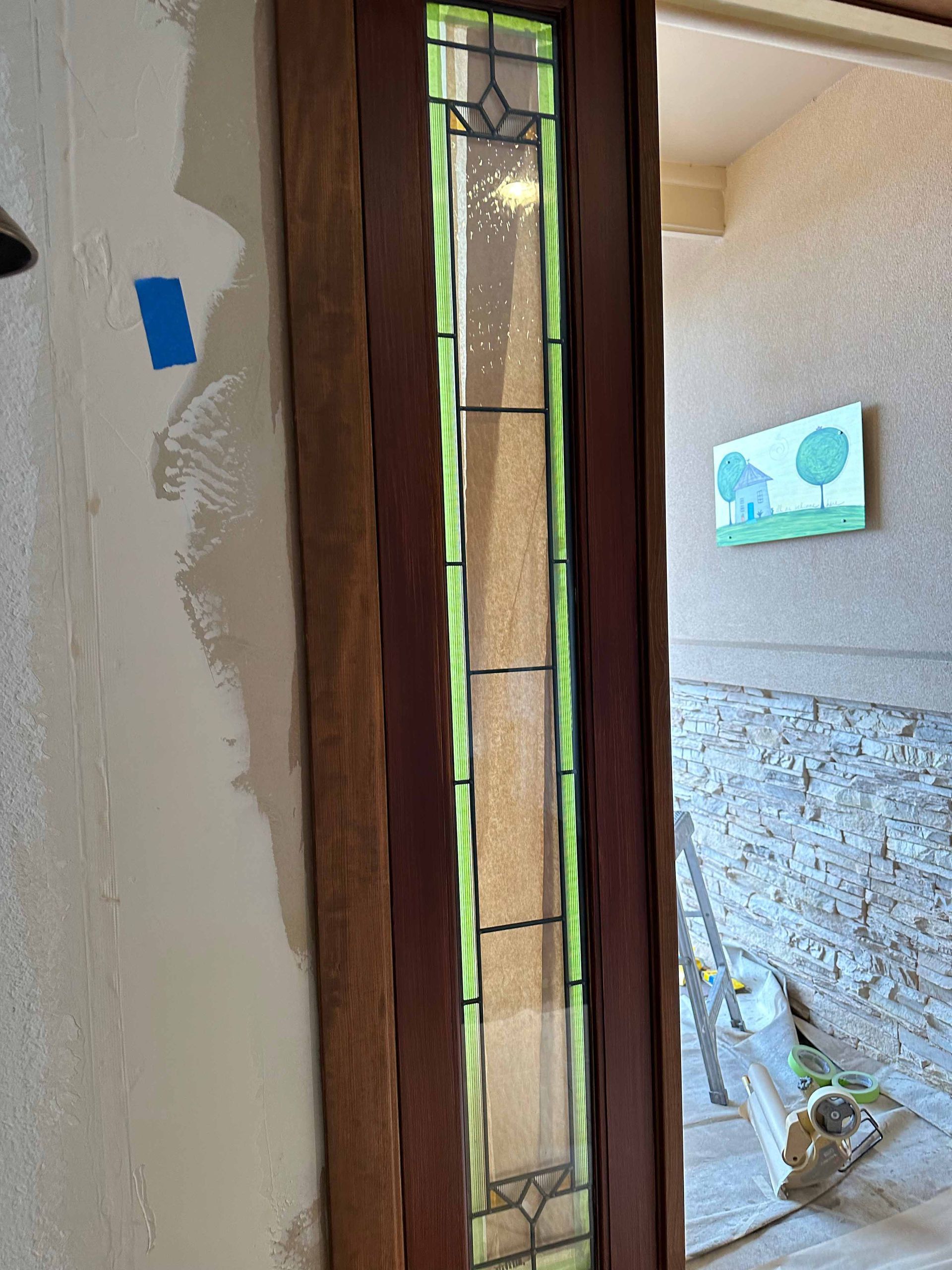 A door with a stained glass window is being installed in a room.