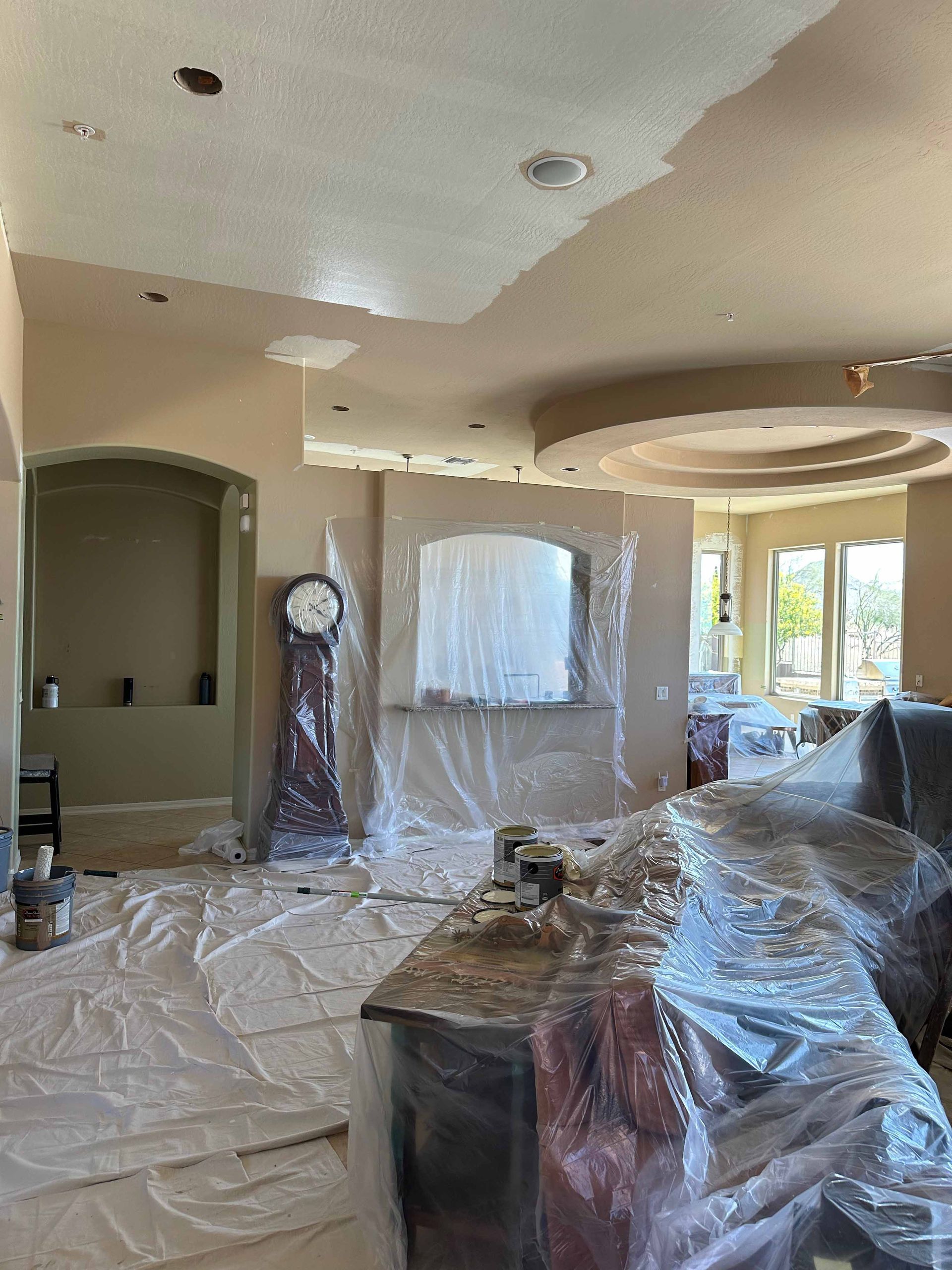 A living room is being painted and covered in plastic.