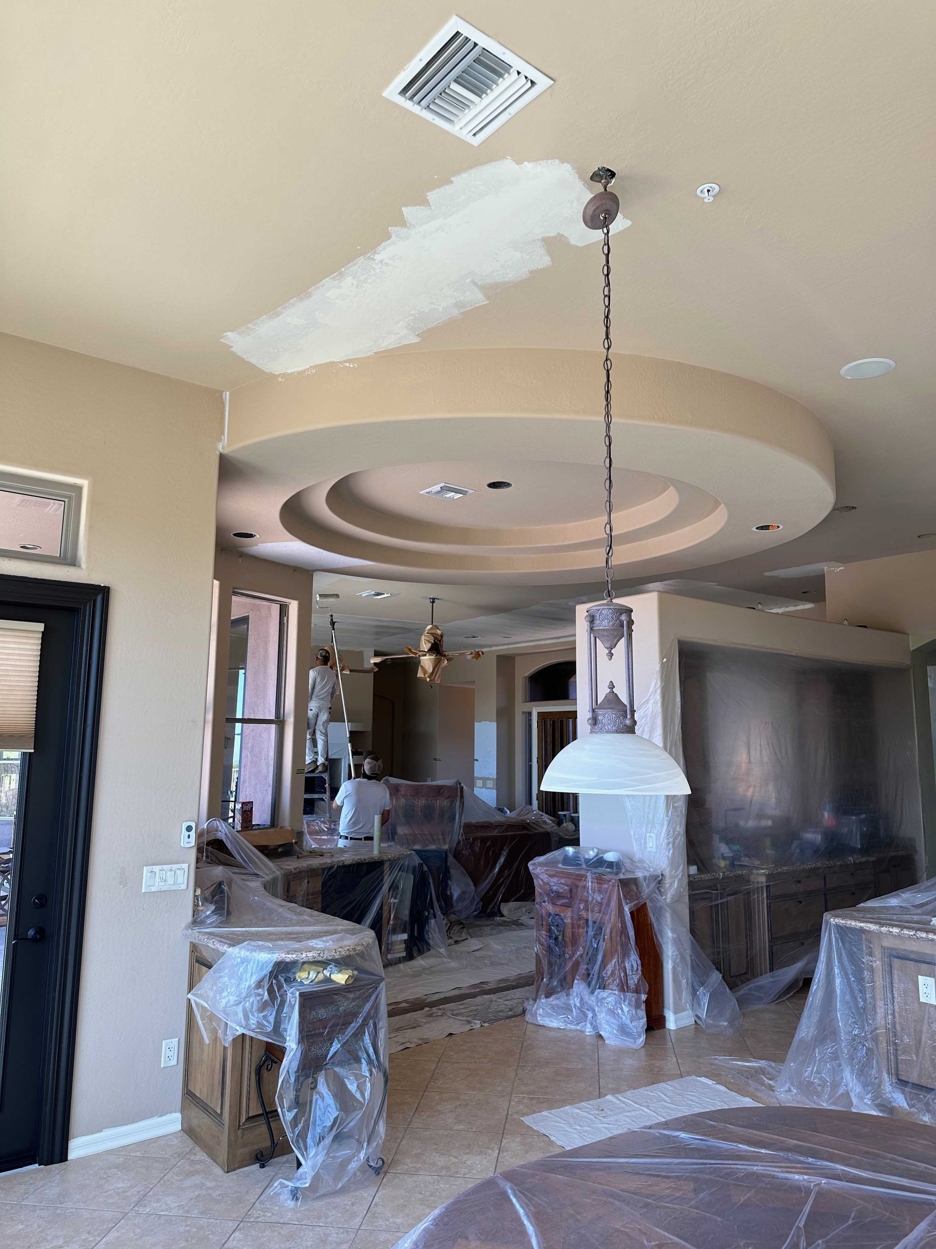 A living room with a ceiling that is being painted