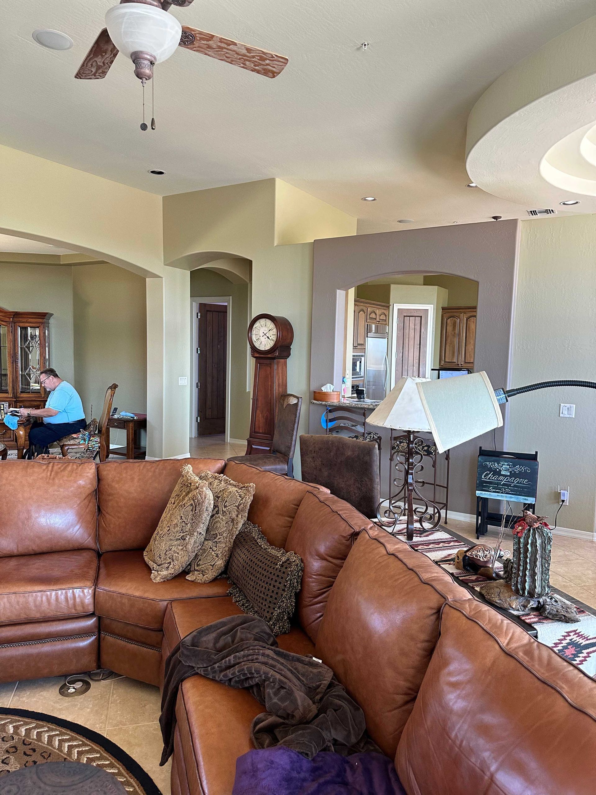 A living room with a brown sectional couch and a ceiling fan