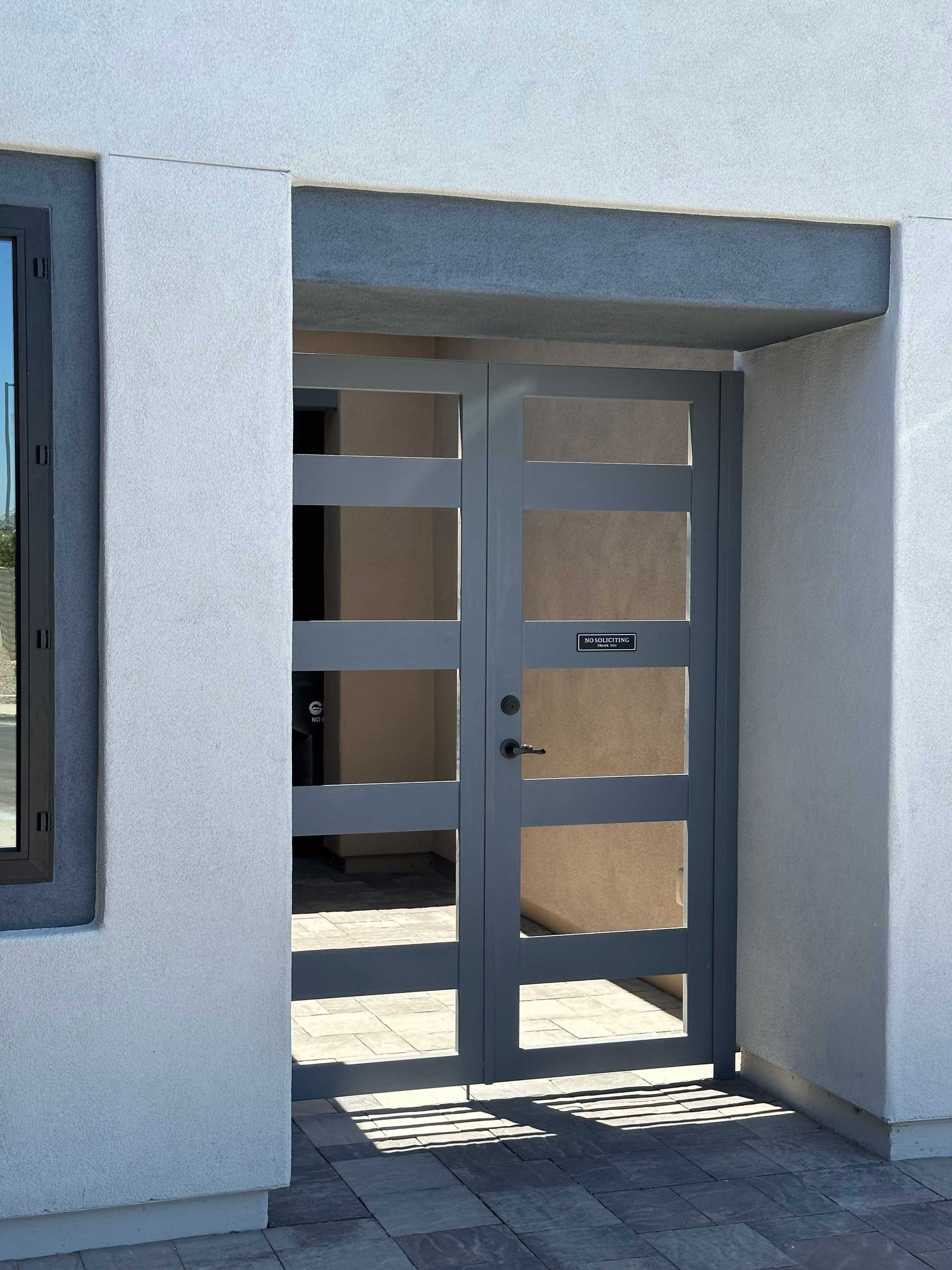 A white building with a gray door and a window