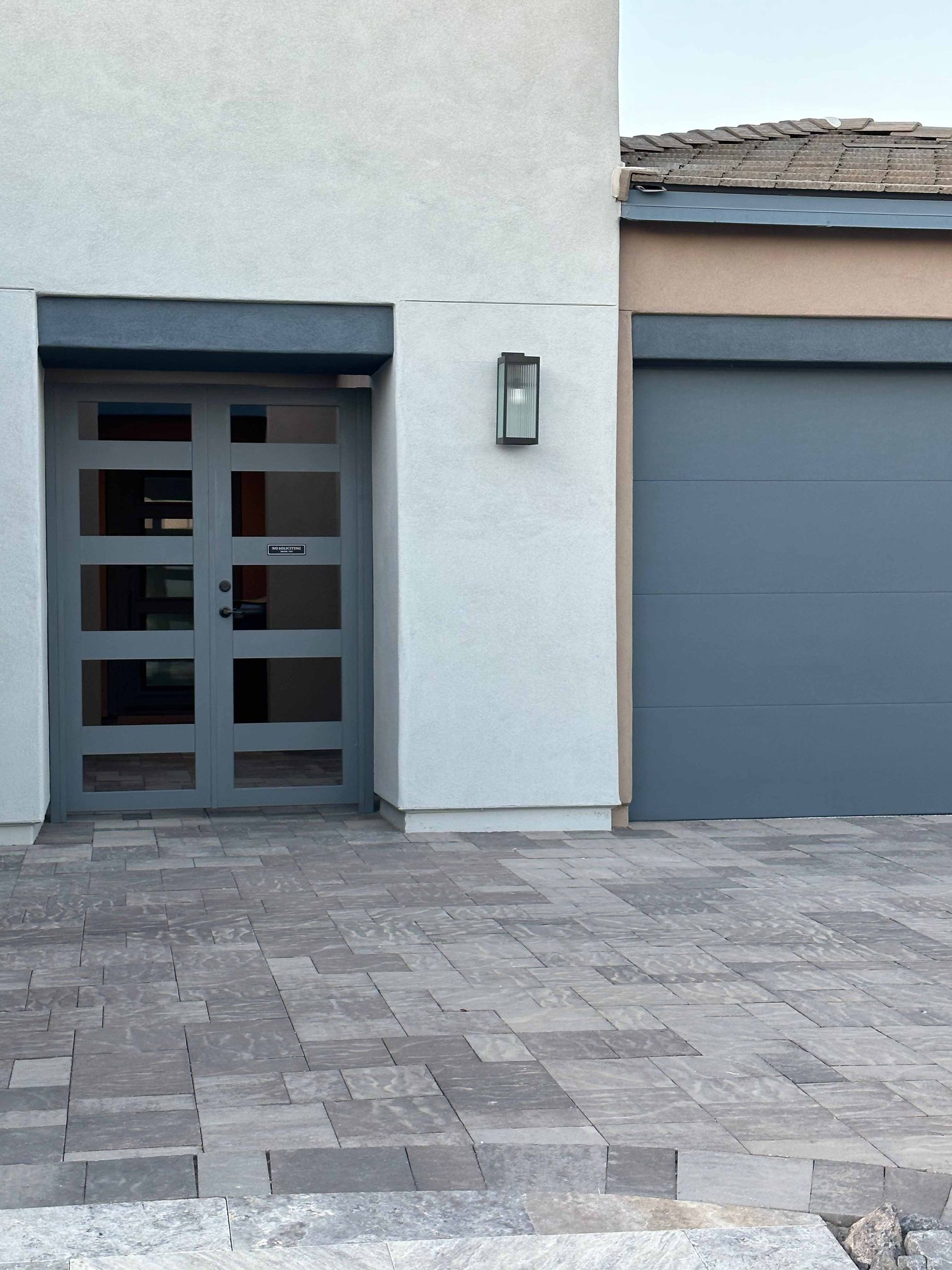 A white building with a gray garage door
