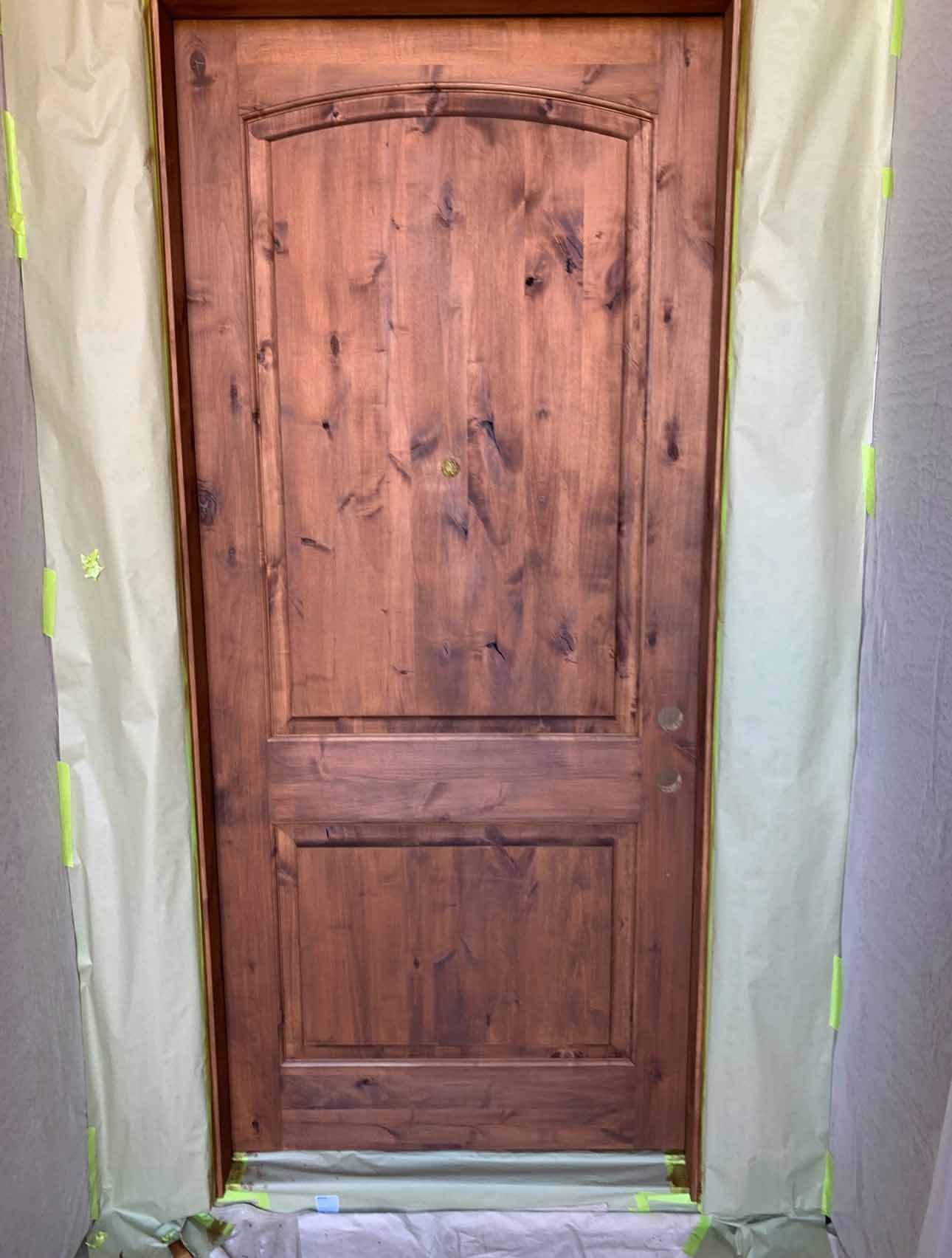 A wooden door is covered with a white cloth and yellow tape.