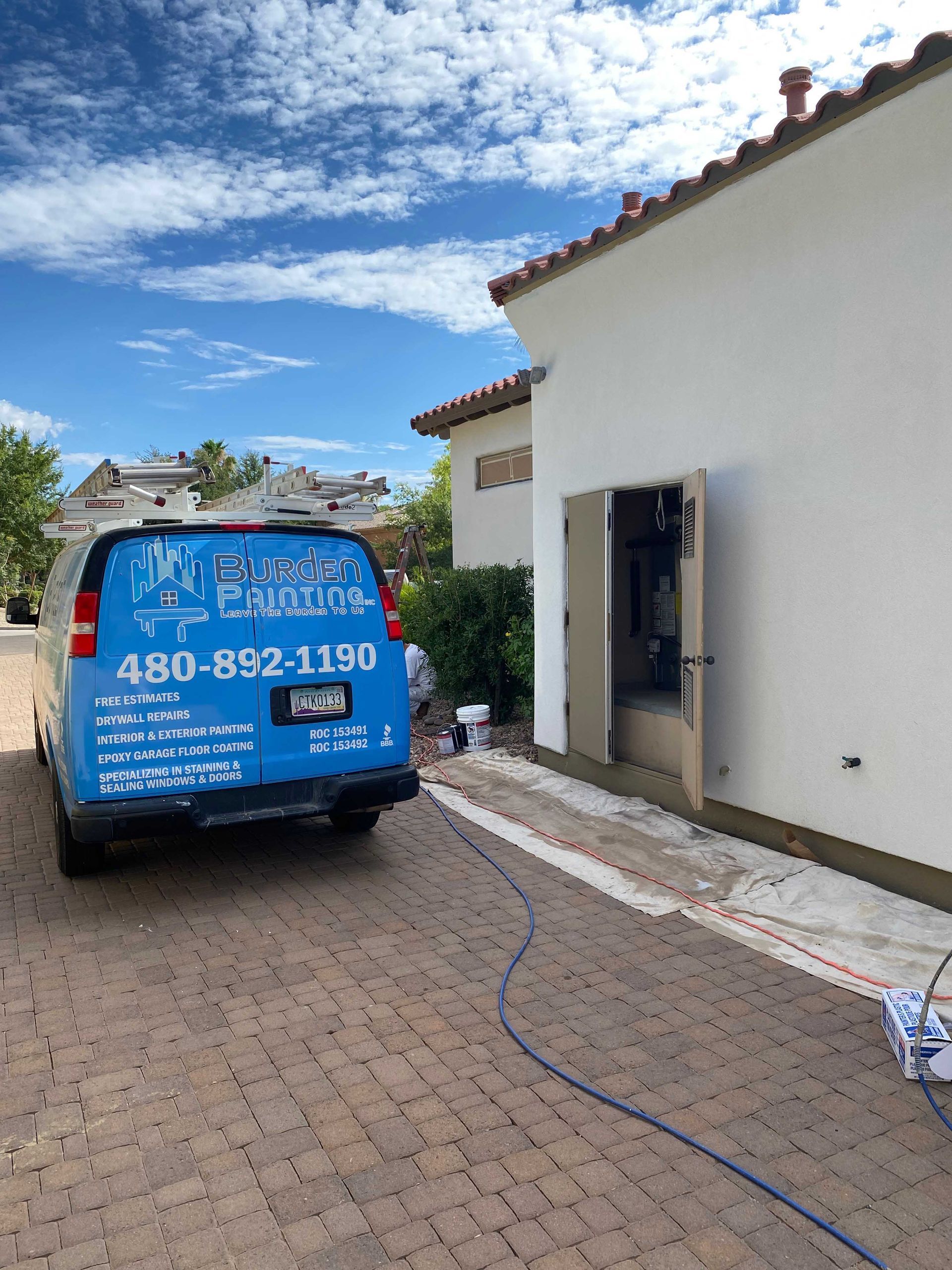 A blue van is parked in front of a white building.