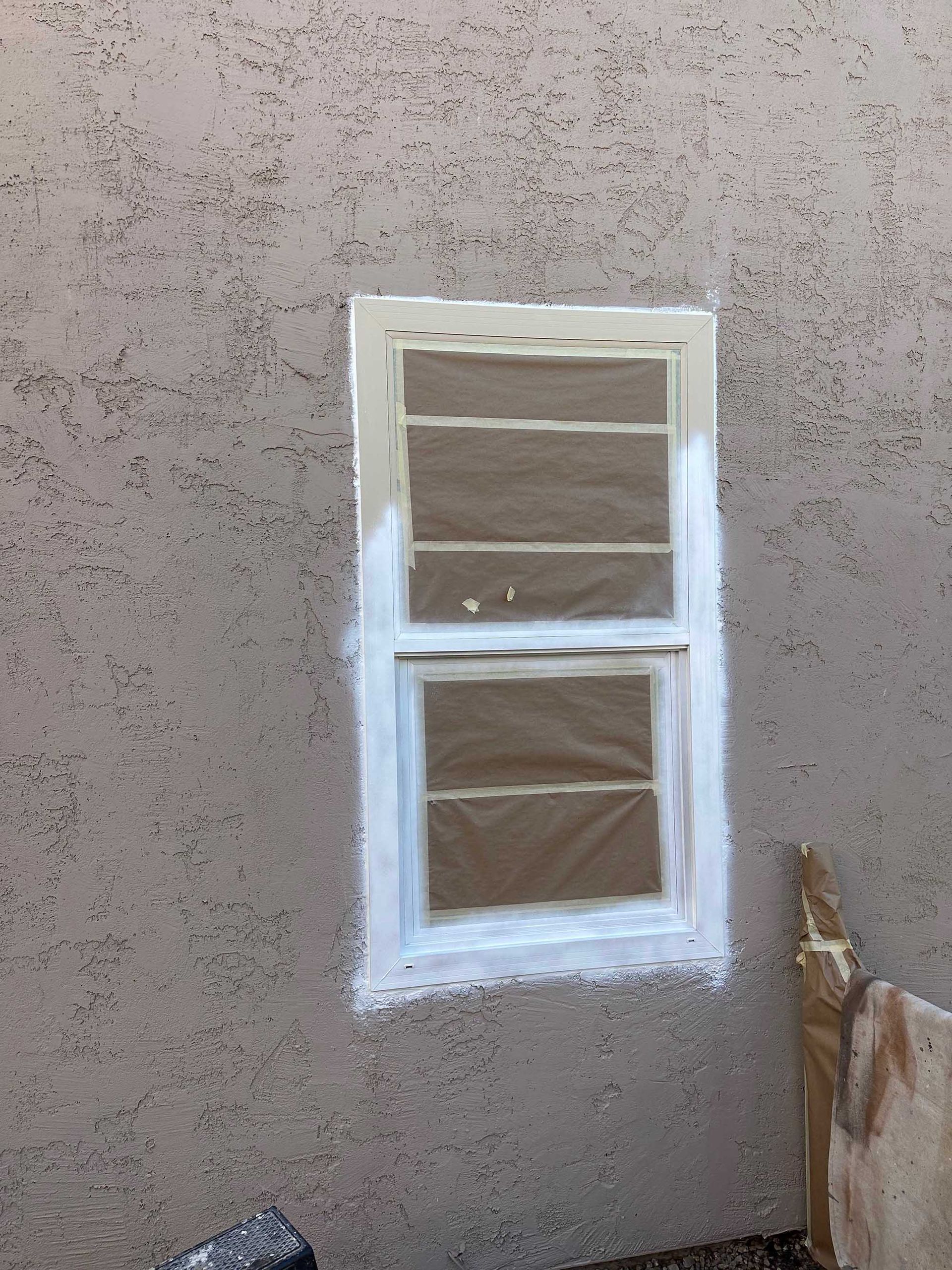 A window is being painted white on the side of a building.