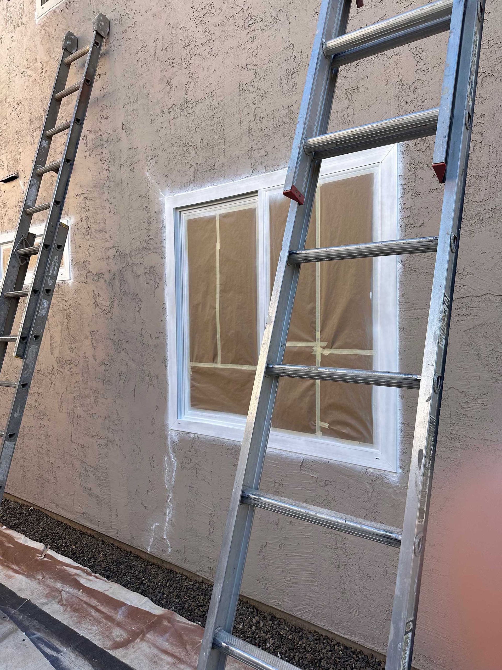 A ladder is leaning against a wall next to a window.